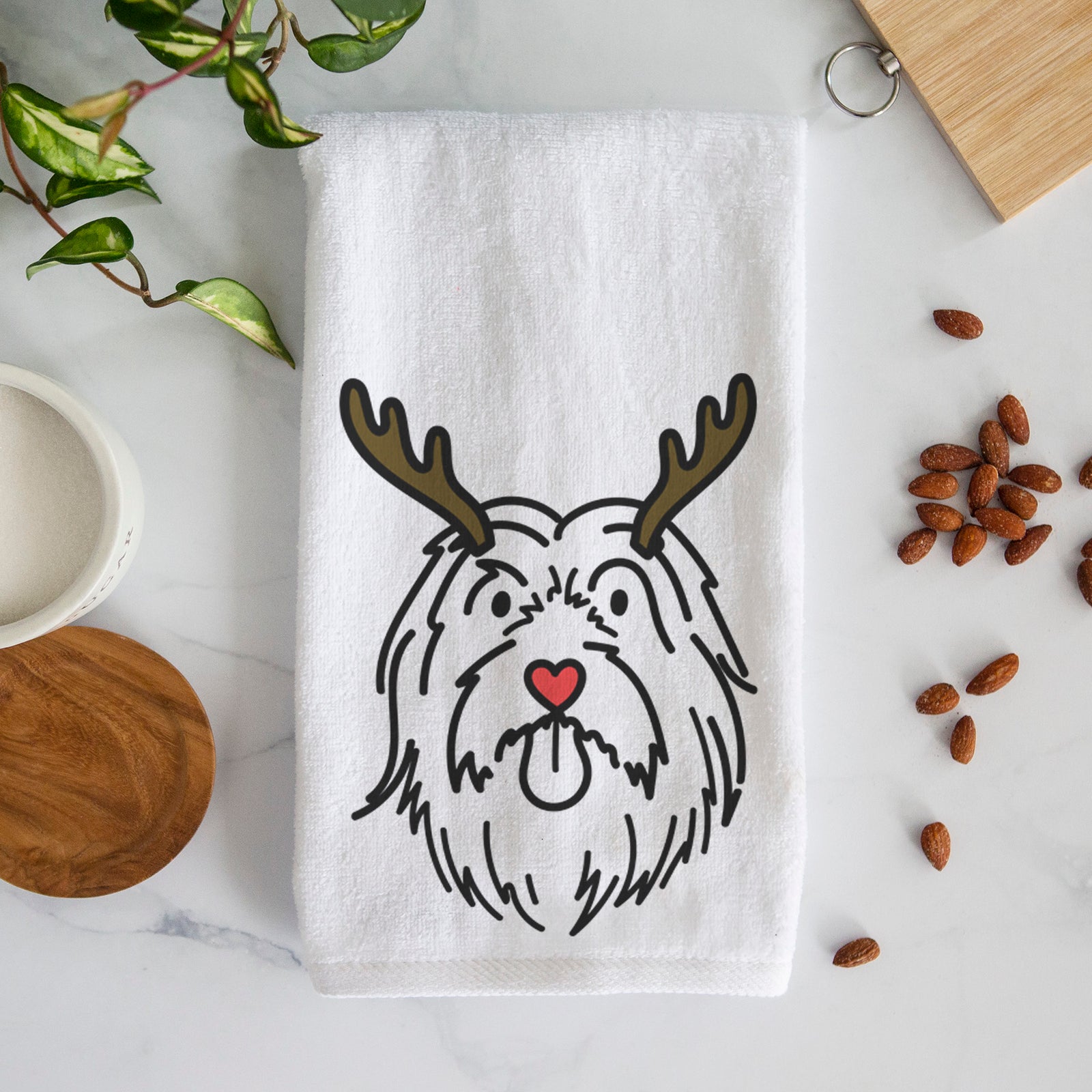 Minimalist line drawing of Tucker the Bearded Collie with reindeer antlers and a red nose on a decorative hand towel