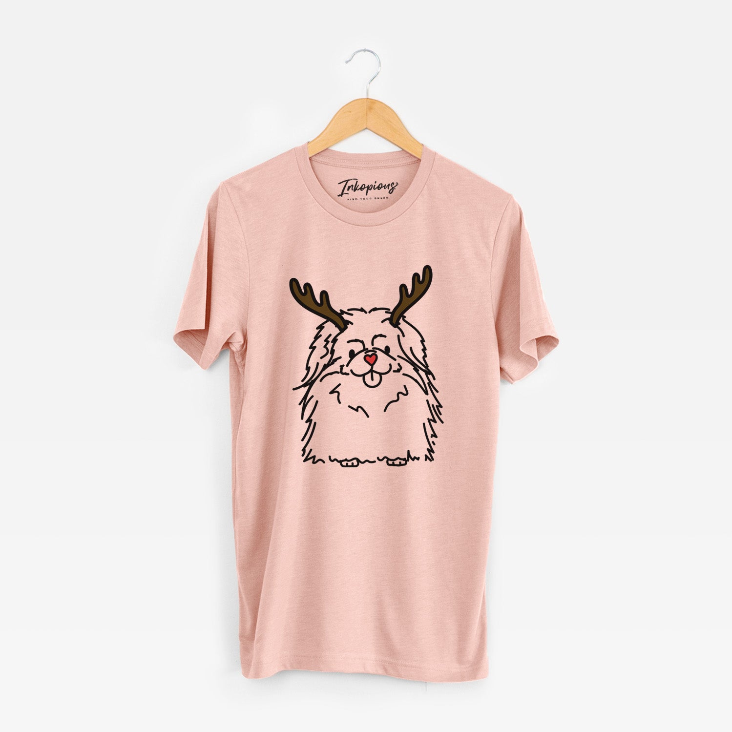 Minimalist line drawing of Viv the Pekingese with reindeer antlers and a red nose on a Peach Unisex crewneck