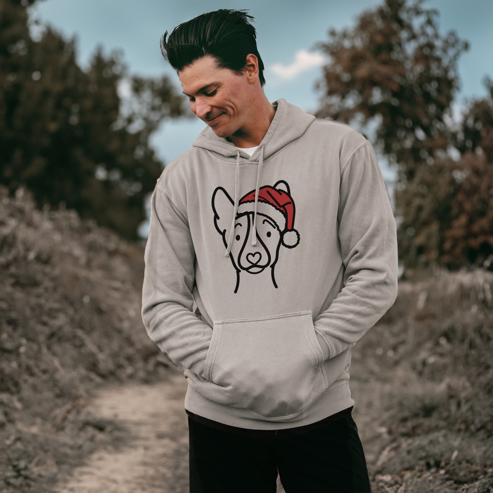 Minimalist line drawing of a Basenji wearing a Santa hat on a Cement Unisex pigment dyed hoodie, worn by a man