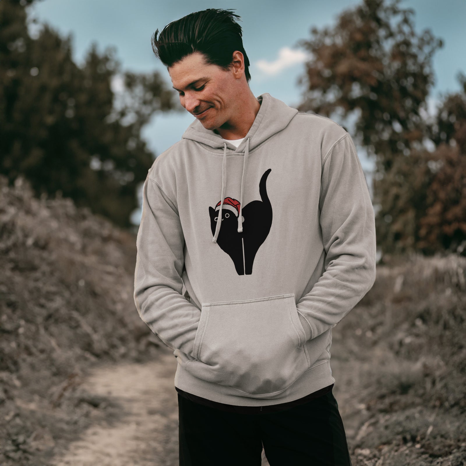 Minimalist line drawing of Bella the Black Cat wearing a Santa hat on a Cement Unisex pigment dyed hoodie, worn by a man