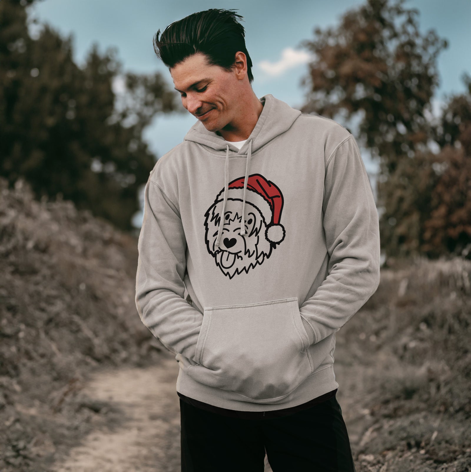 Minimalist line drawing of a Catalan Sheepdog wearing a Santa hat on a Cement Unisex pigment dyed hoodie, worn by a man