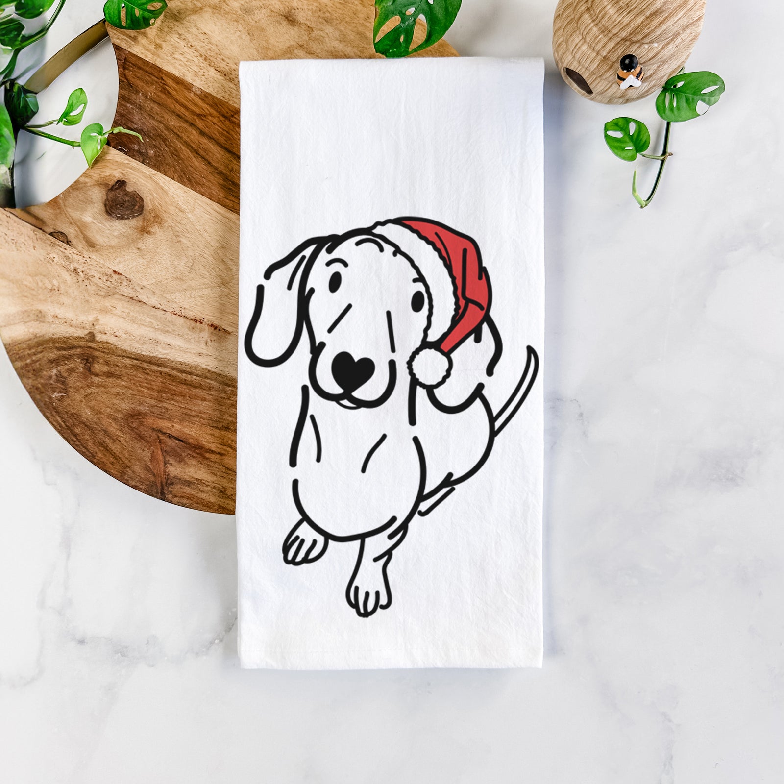 Minimalist line drawing of Moxie the Dachshund wearing a Santa hat on a tea towel