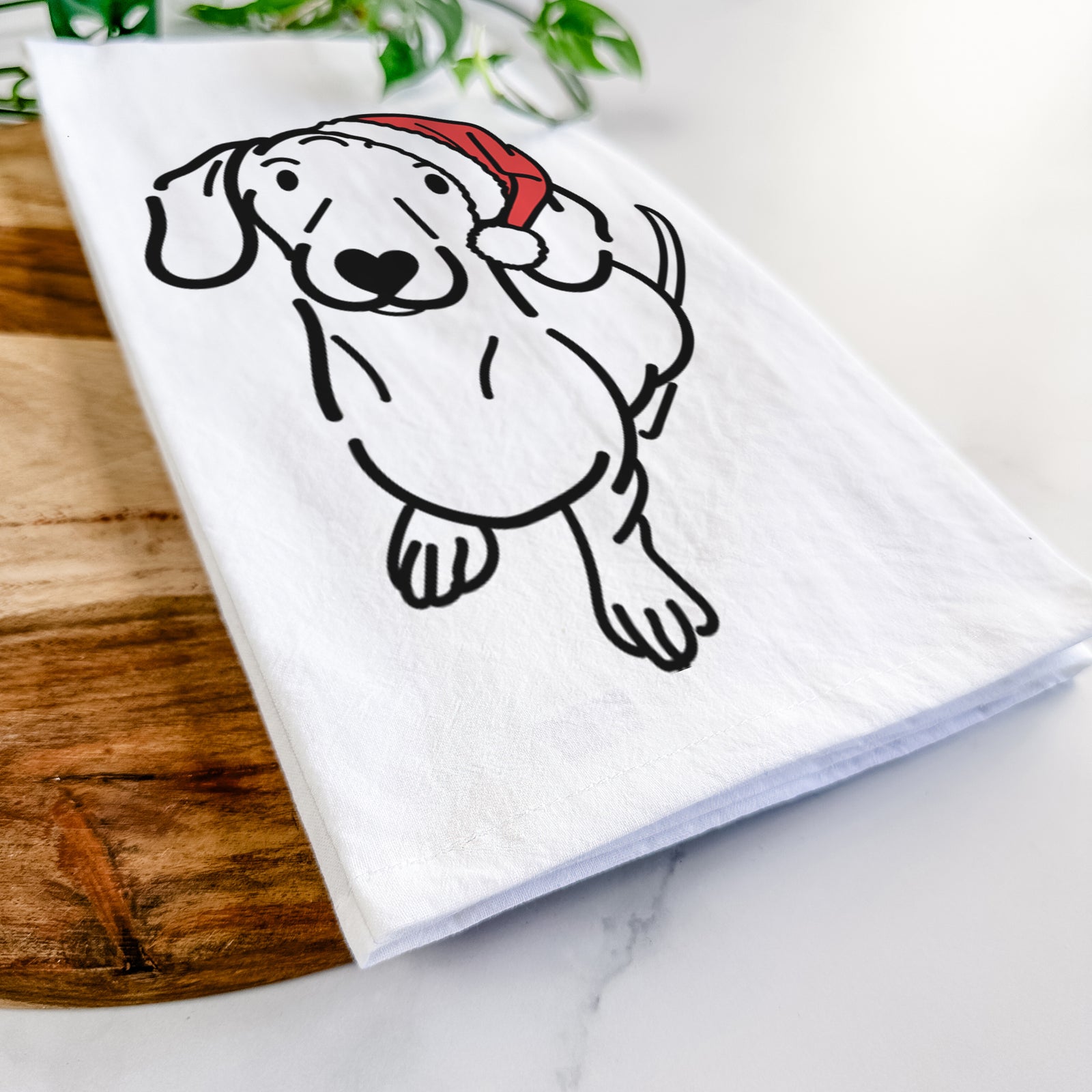 Minimalist line drawing of Moxie the Dachshund wearing a Santa hat on a tea towel