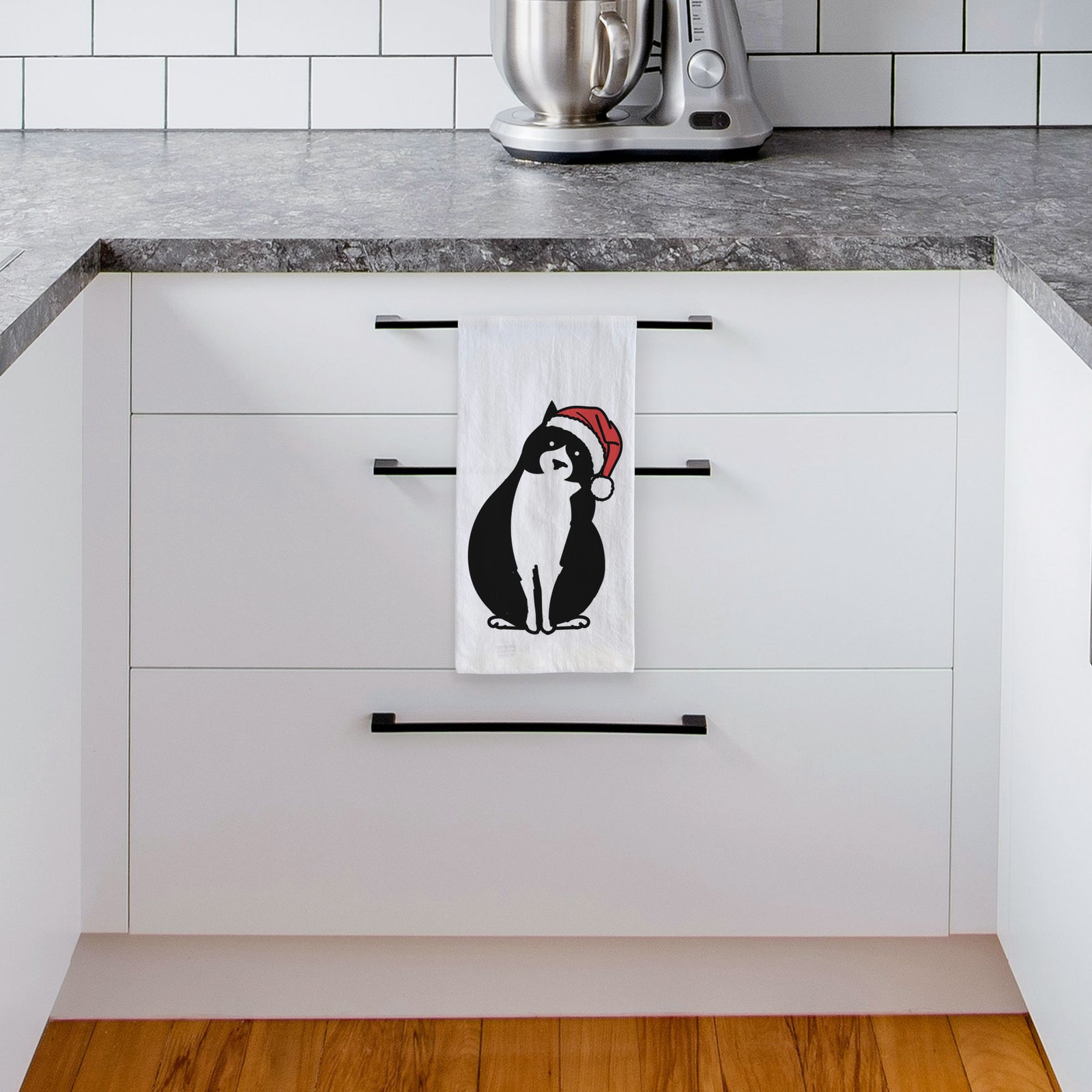 Minimalist line drawing of Oliver the Tuxedo Cat wearing a Santa hat on a tea towel, hanging on an oven door in a kitchen