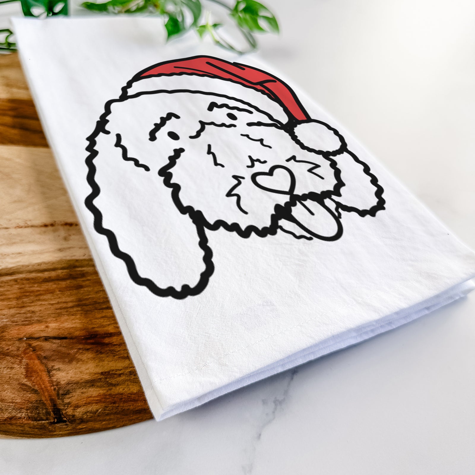 Minimalist line drawing of Ruby the Bernedoodle wearing a Santa hat on a tea towel