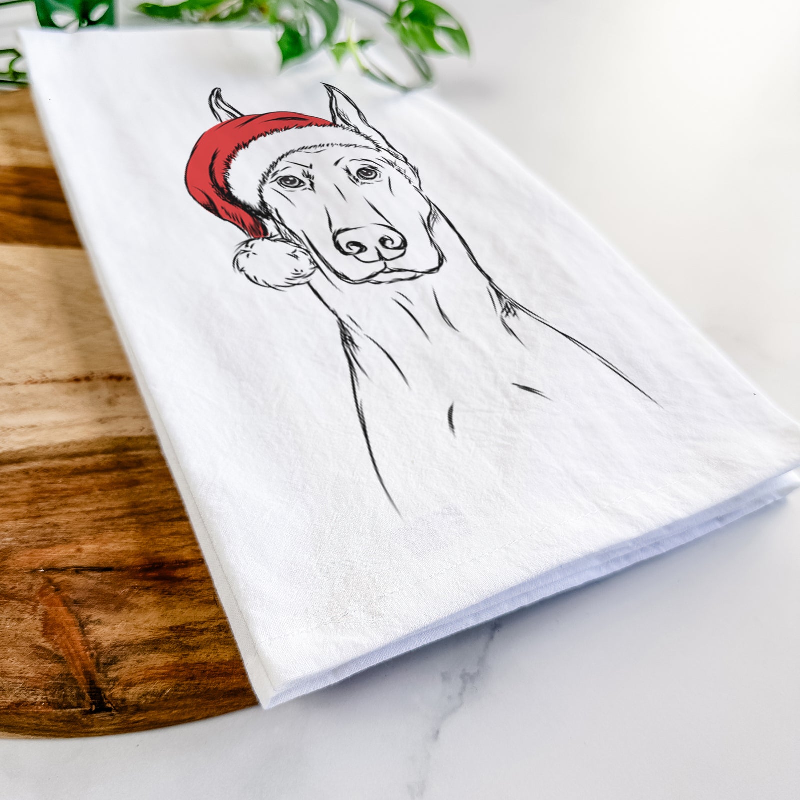 Hand-drawn sketch of Ace the Doberman Pinscher wearing a Santa hat on a tea towel