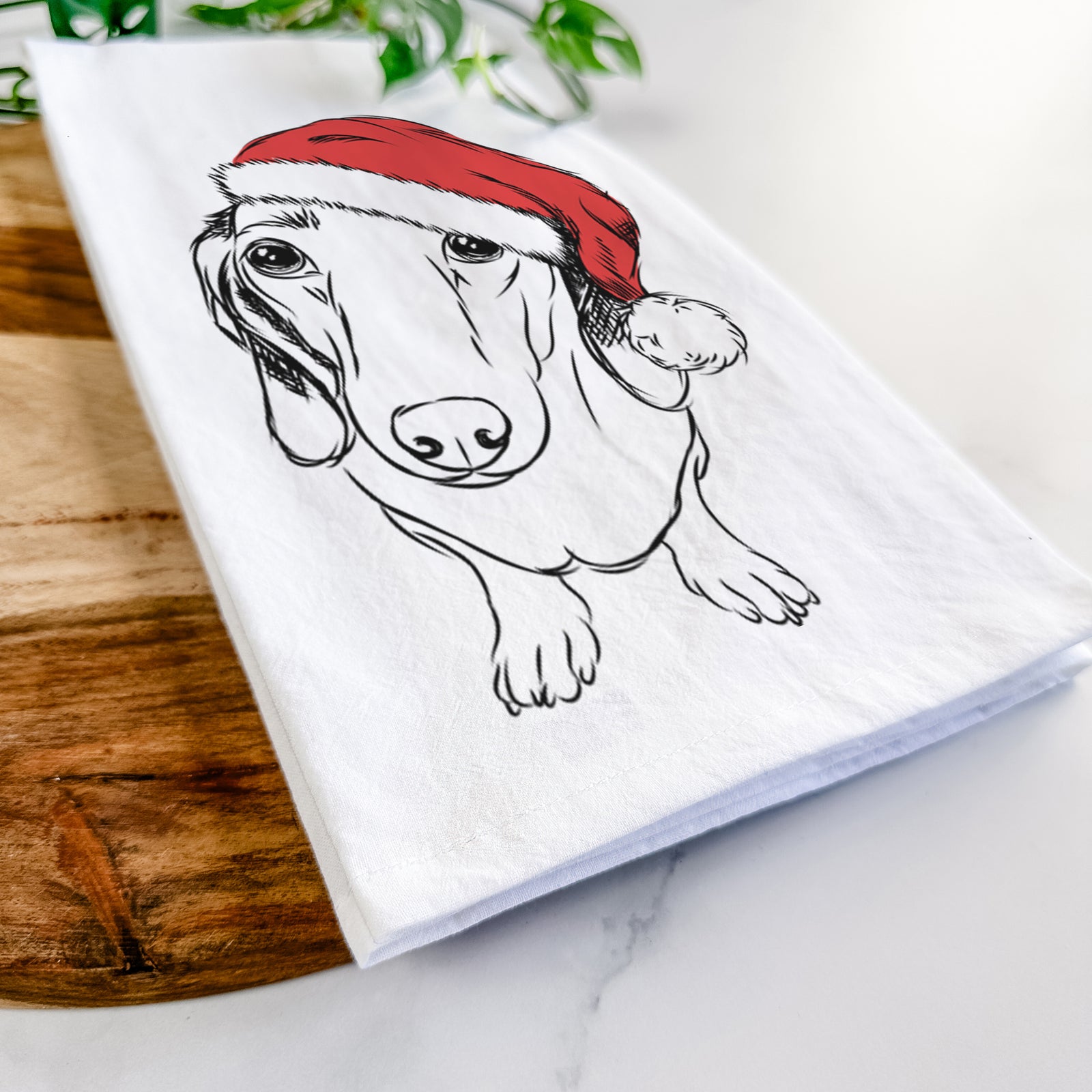 Hand-drawn sketch of Annabelle the Dachshund wearing a Santa hat on a tea towel