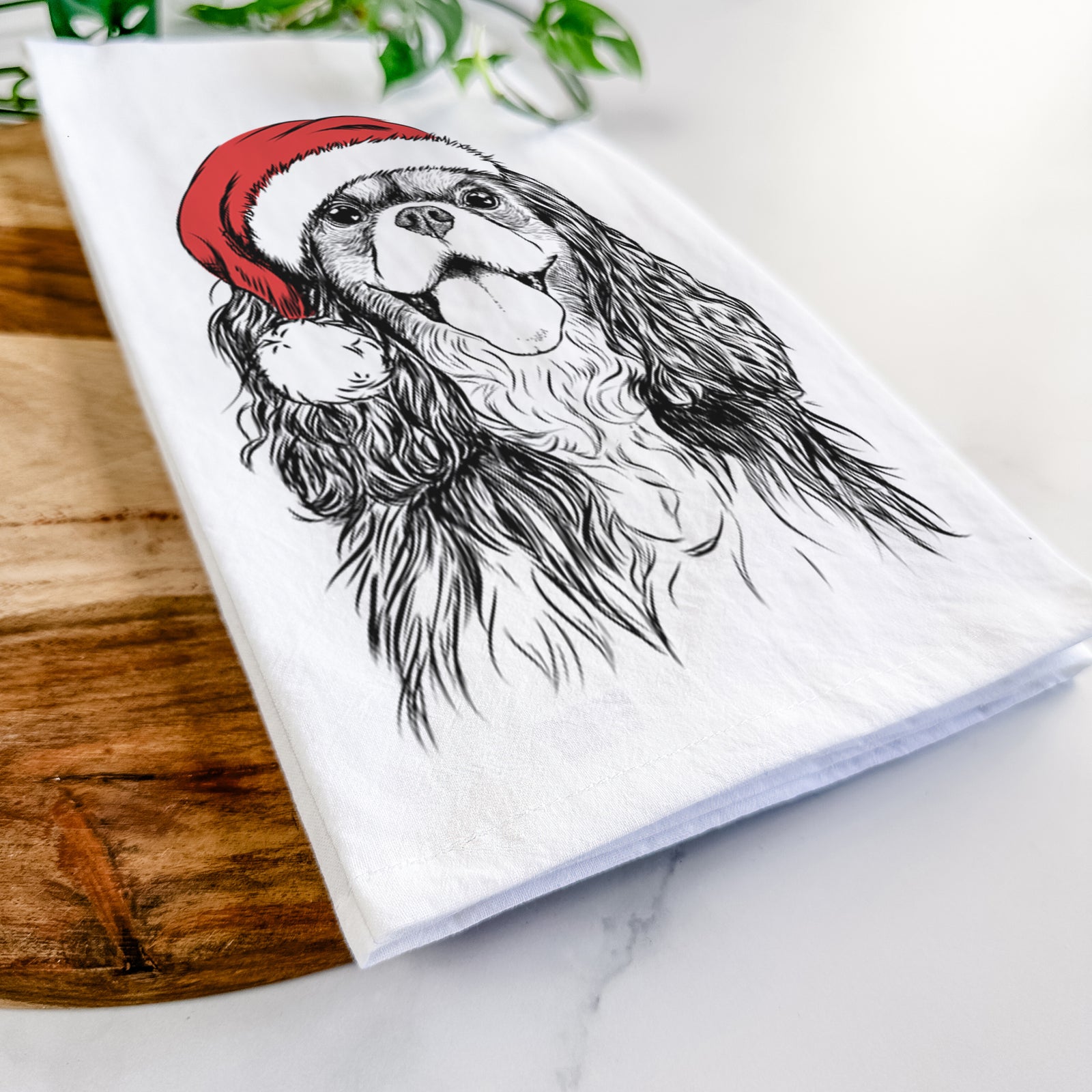 Hand-drawn sketch of Brandy the Cavalier King Charles Spaniel wearing a Santa hat on a tea towel