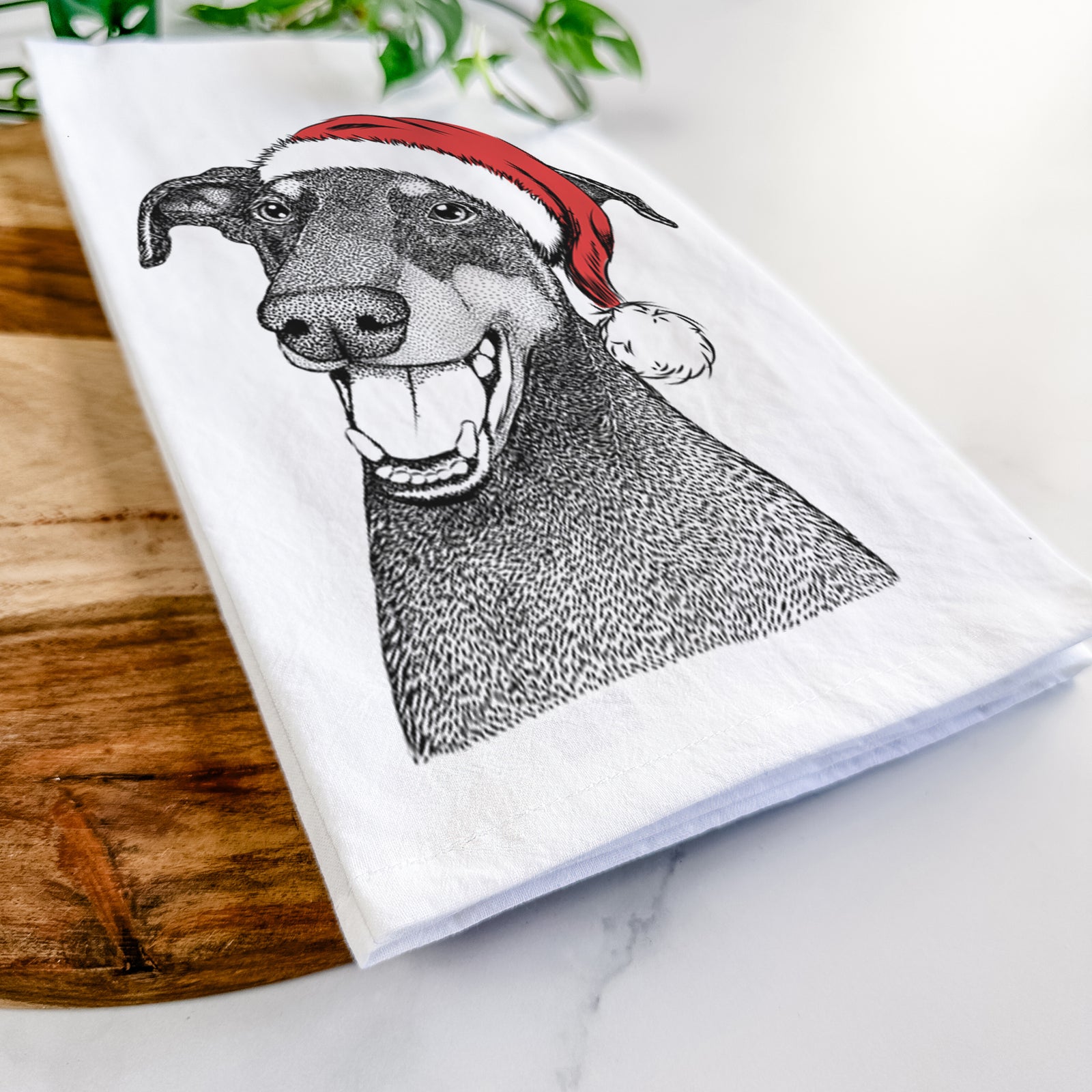 Hand-drawn sketch of Bunnie the Doberman Pinscher wearing a Santa hat on a tea towel
