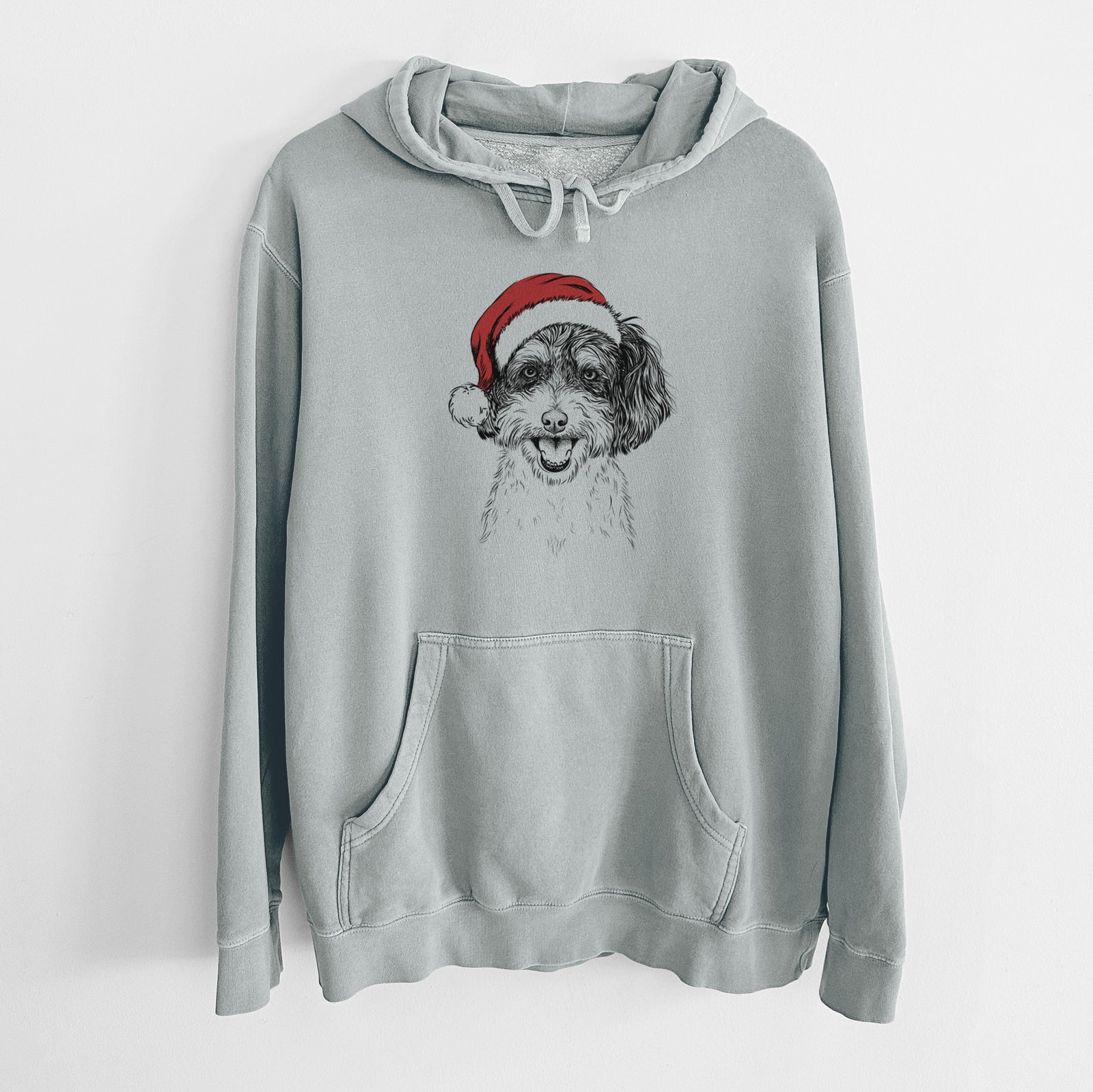 Hand-drawn sketch of Carlos the Cavapoo wearing a Santa hat on a Sage Unisex pigment dyed hoodie