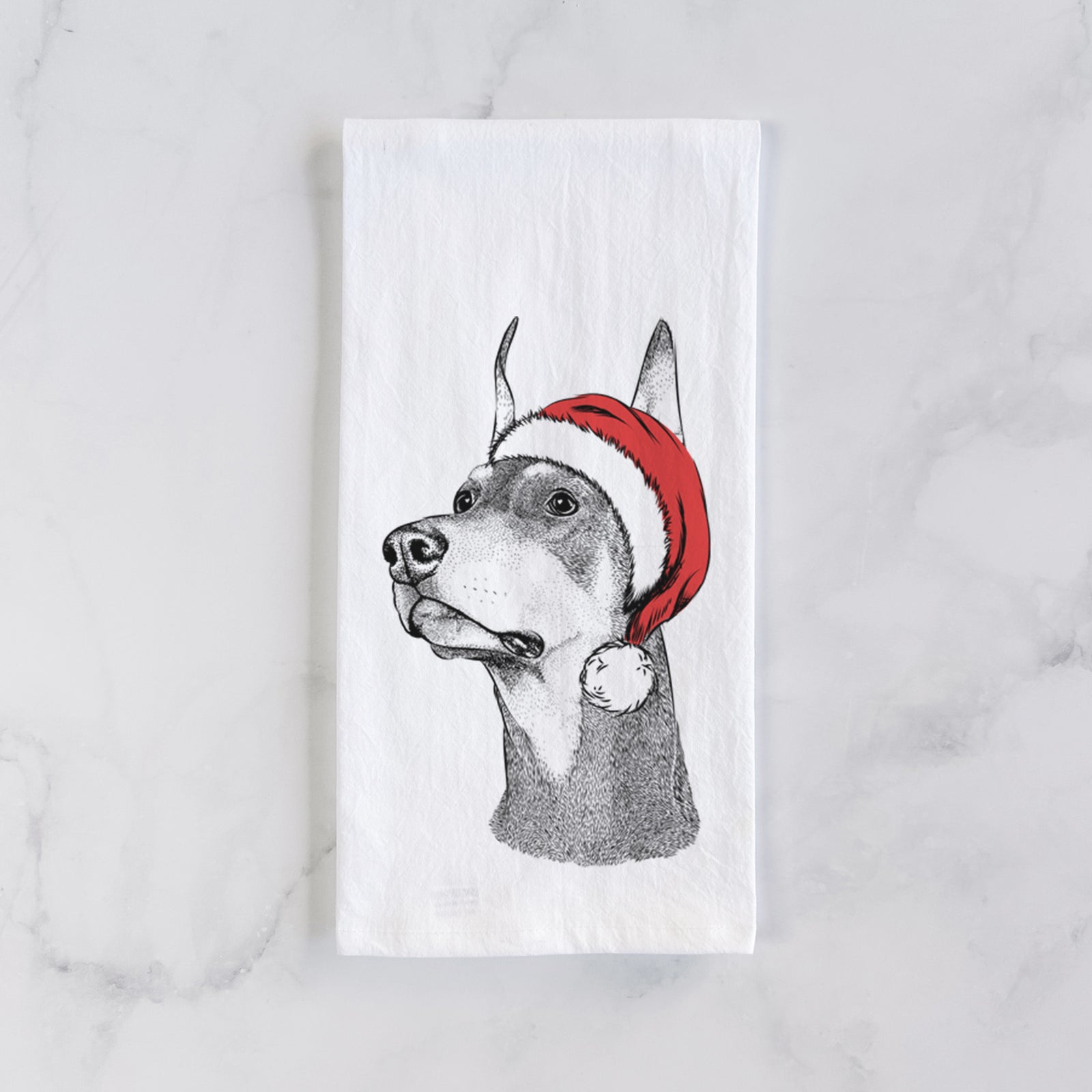 Hand-drawn sketch of Cenza the Doberman Pinscher wearing a Santa hat on a tea towel