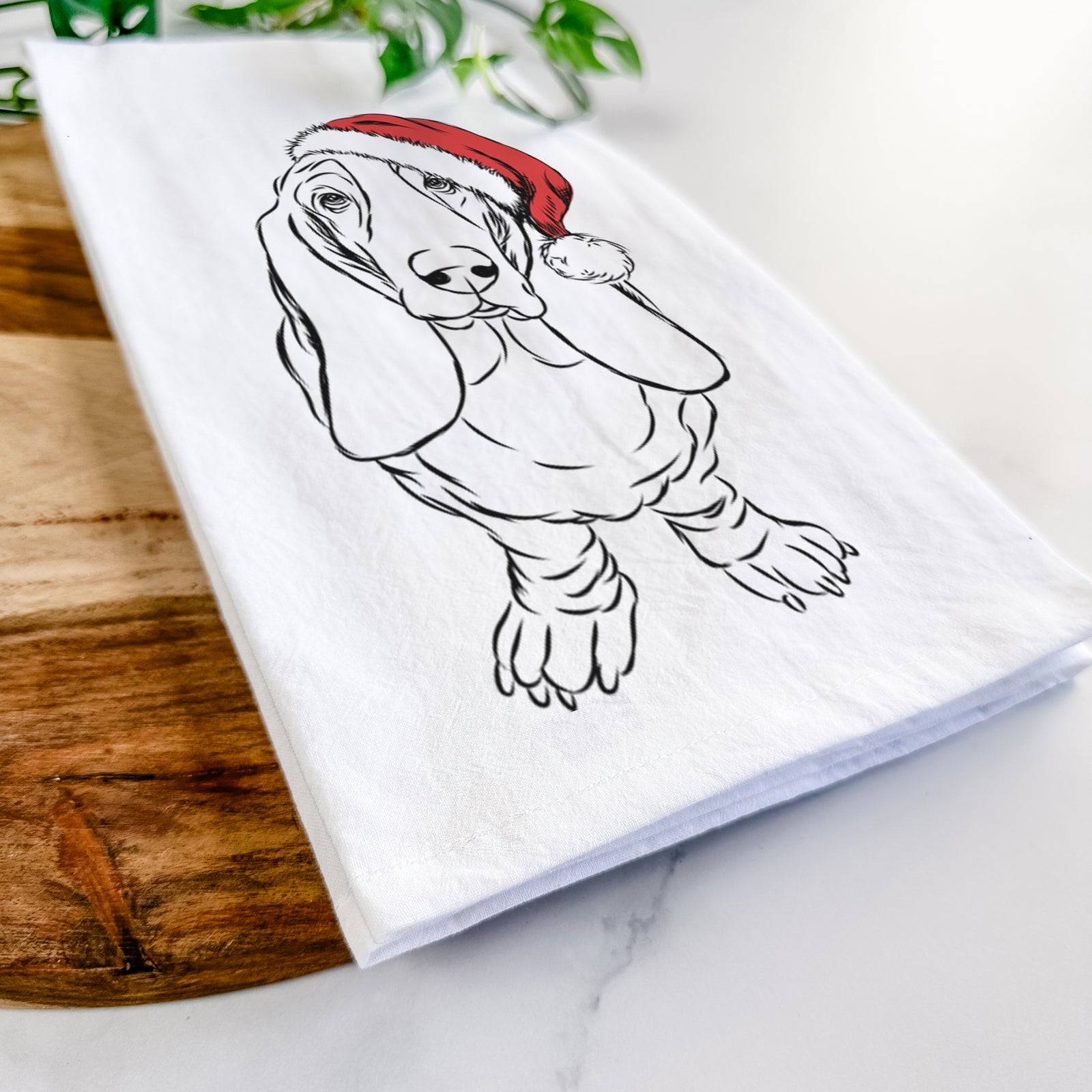Hand-drawn sketch of Charlie the Basset Hound wearing a Santa hat on a tea towel