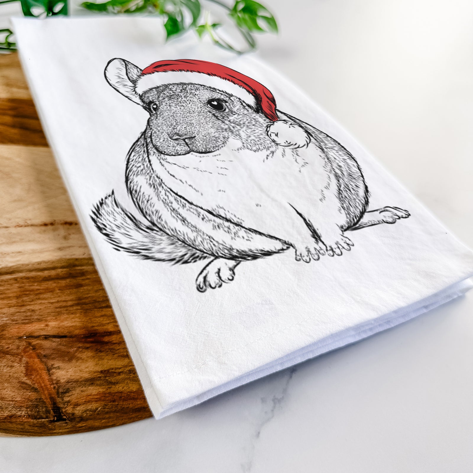 Hand-drawn sketch of Cheddar the Chinchilla wearing a Santa hat on a tea towel