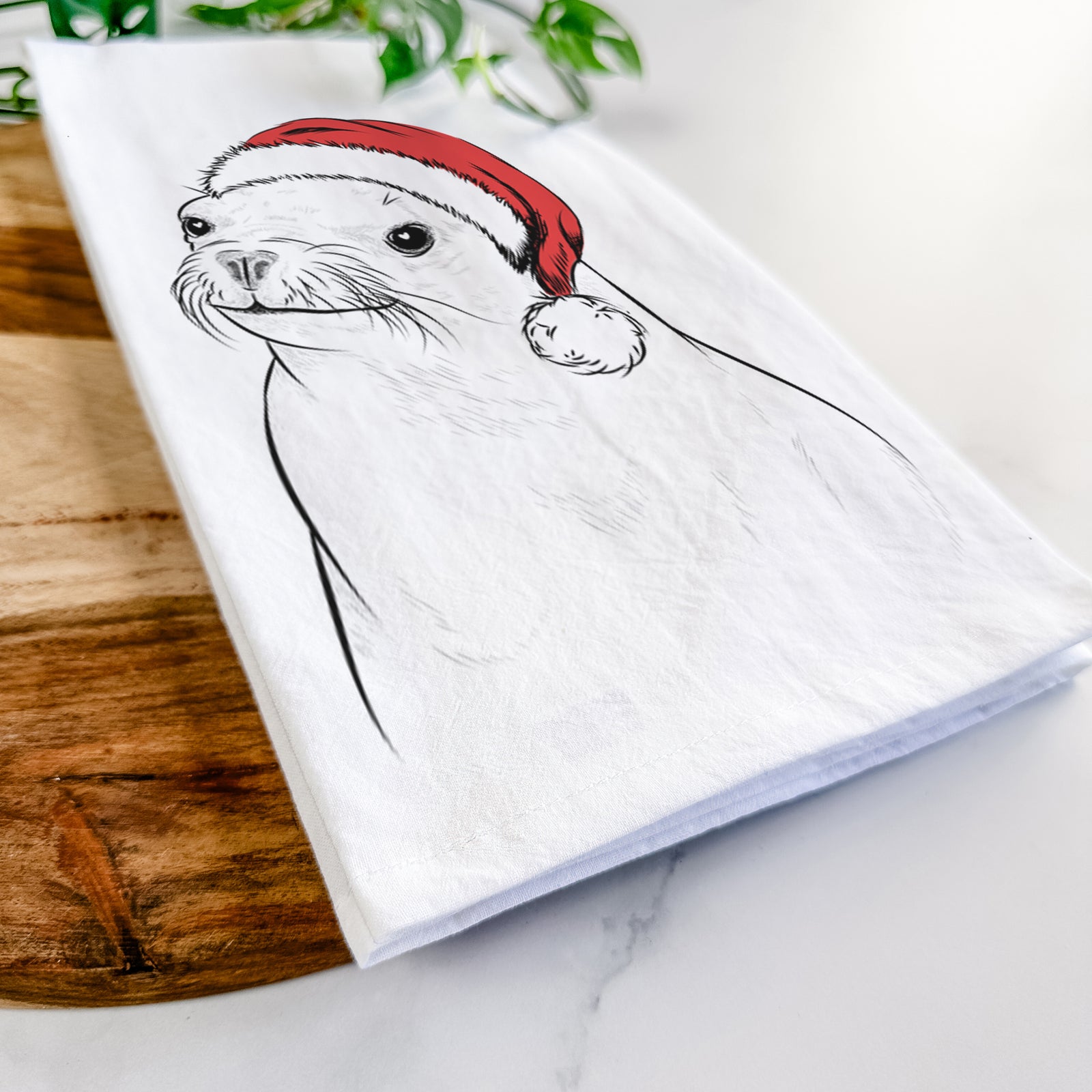 Hand-drawn sketch of Chip the California Sea Lion wearing a Santa hat on a tea towel