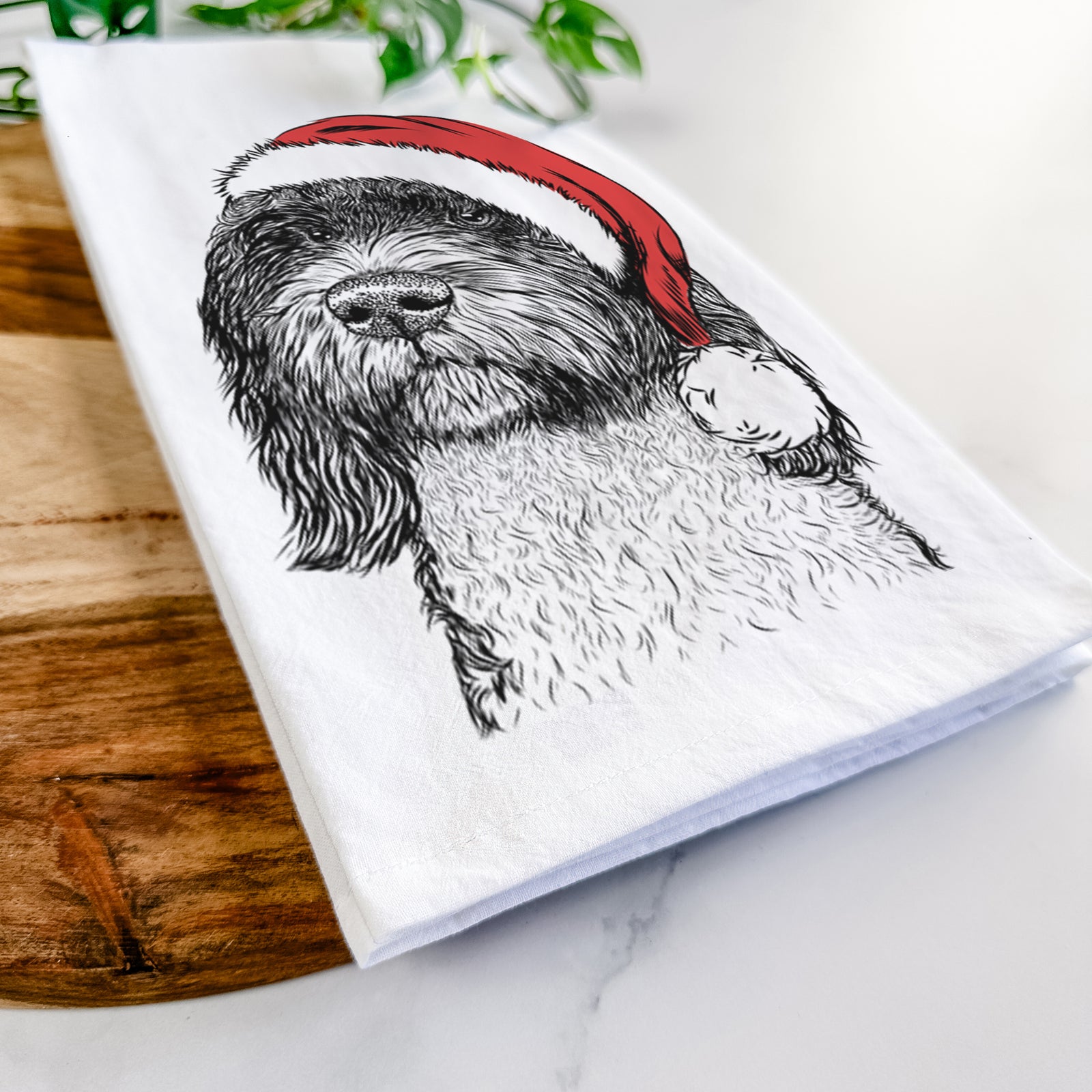 Hand-drawn sketch of Chris the Portuguese Water Dog wearing a Santa hat on a tea towel