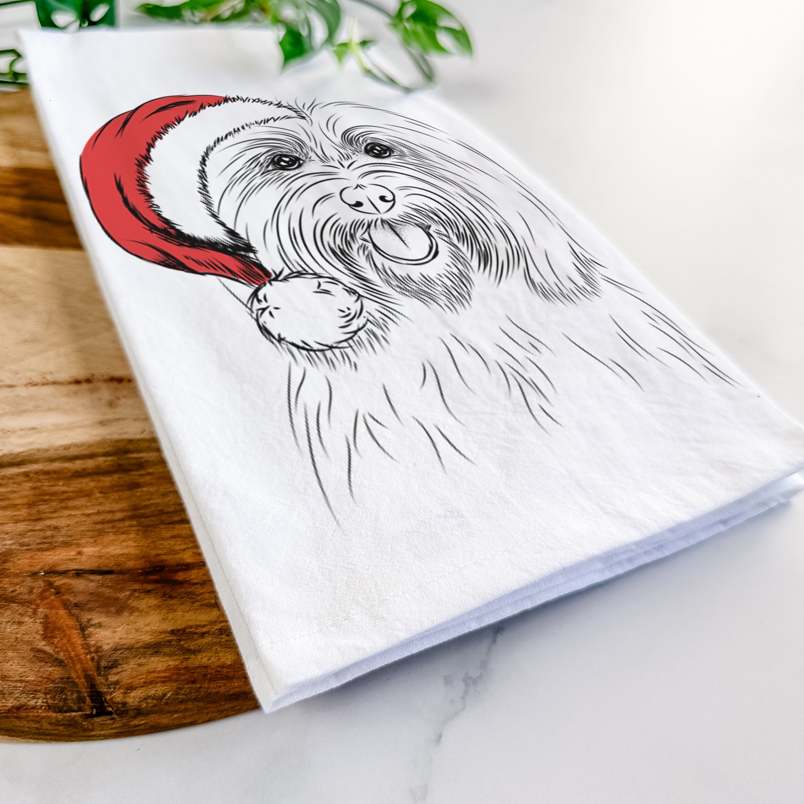 Hand-drawn sketch of Claude the Coton de Tulear wearing a Santa hat on a tea towel