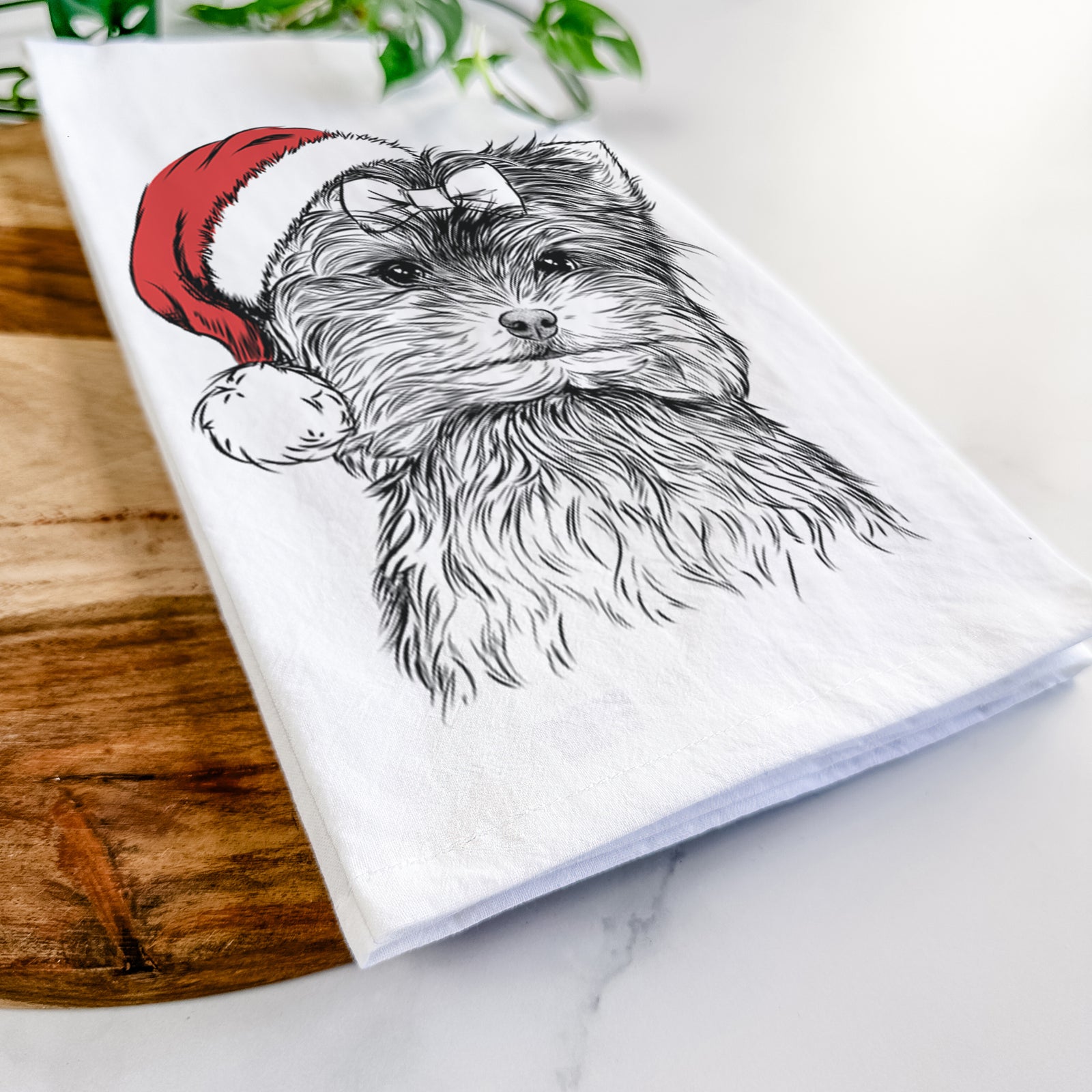 Hand-drawn sketch of Cricket the Biewer Terrier wearing a Santa hat on a tea towel