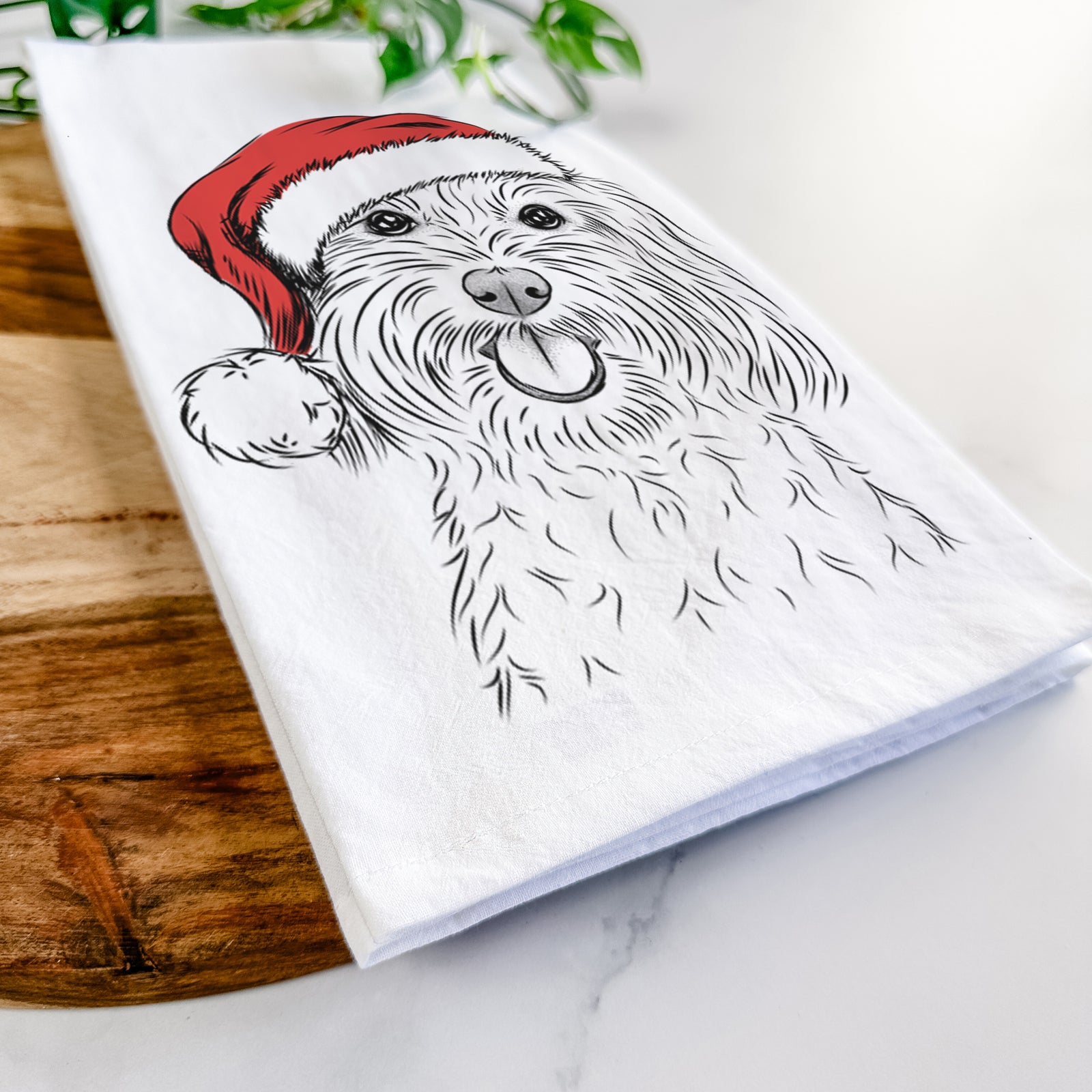 Hand-drawn sketch of Cuddles the Coton de Tulear wearing a Santa hat on a tea towel
