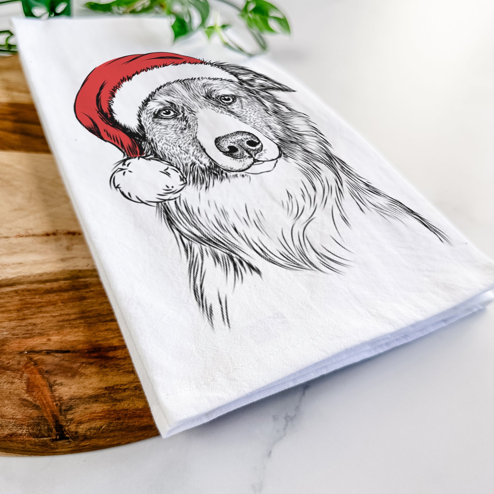 Hand-drawn sketch of Cynder the English Shepherd wearing a Santa hat on a tea towel