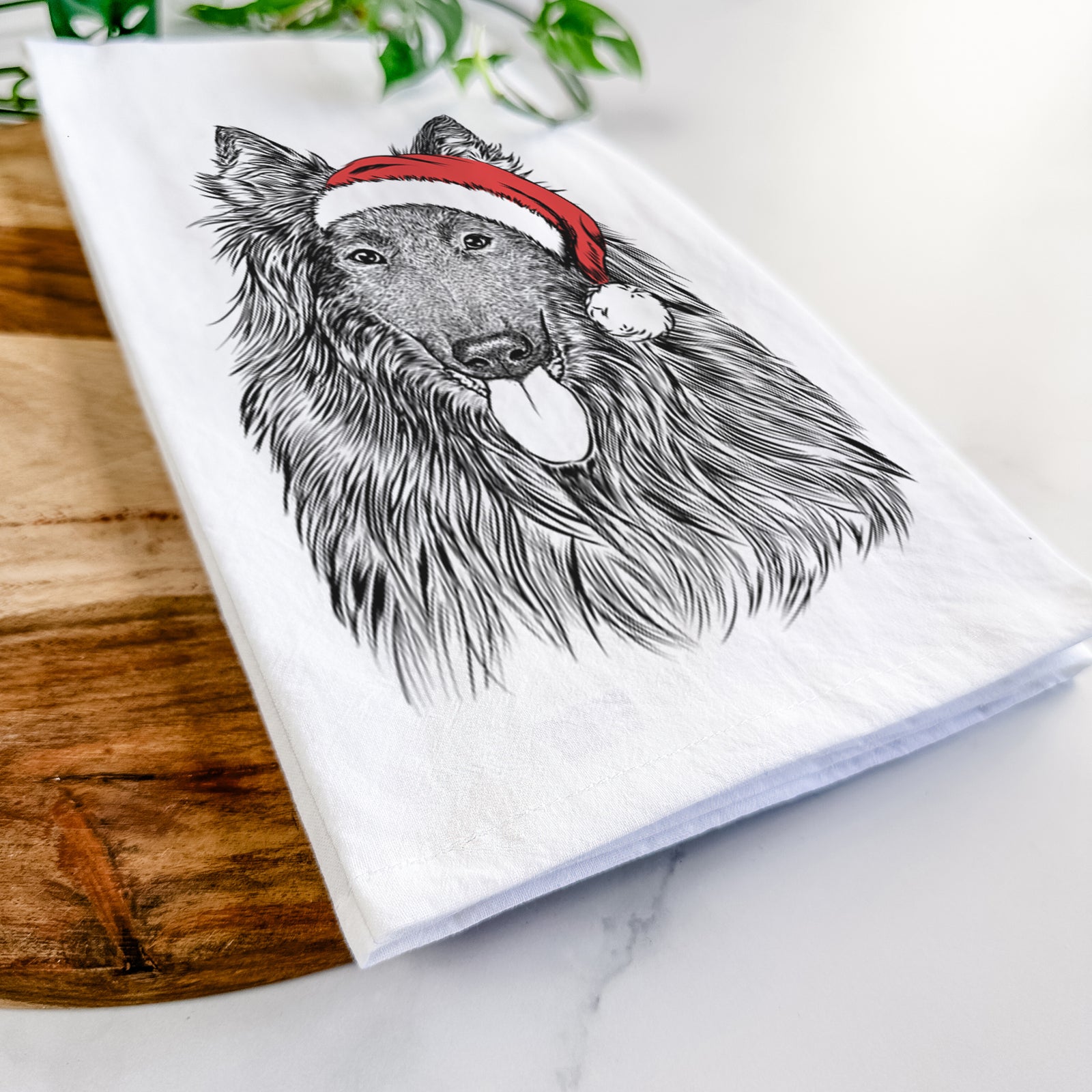 Hand-drawn sketch of Daan the Belgian Shepherd wearing a Santa hat on a tea towel