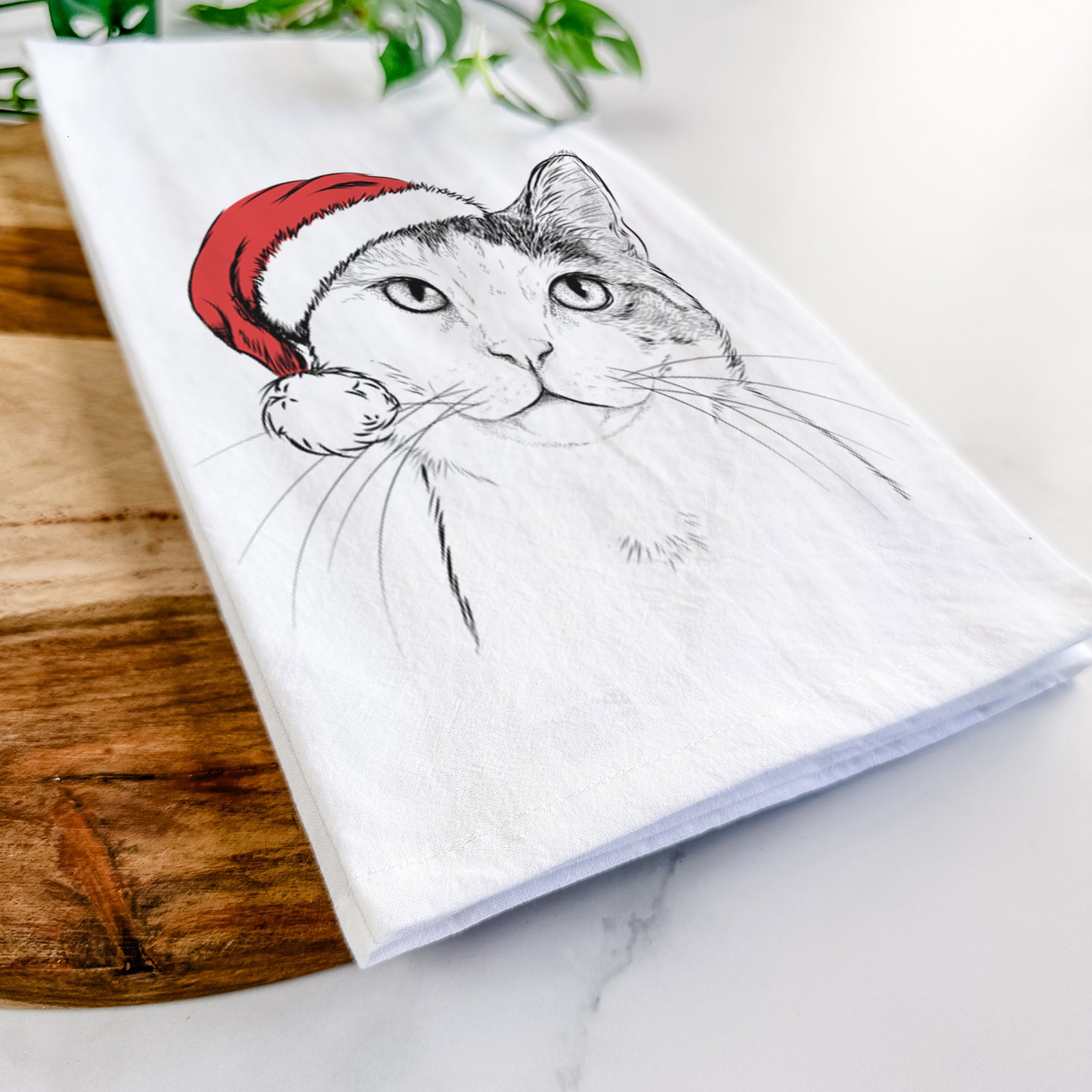 Hand-drawn sketch of Denver the Calico Cat wearing a Santa hat on a tea towel