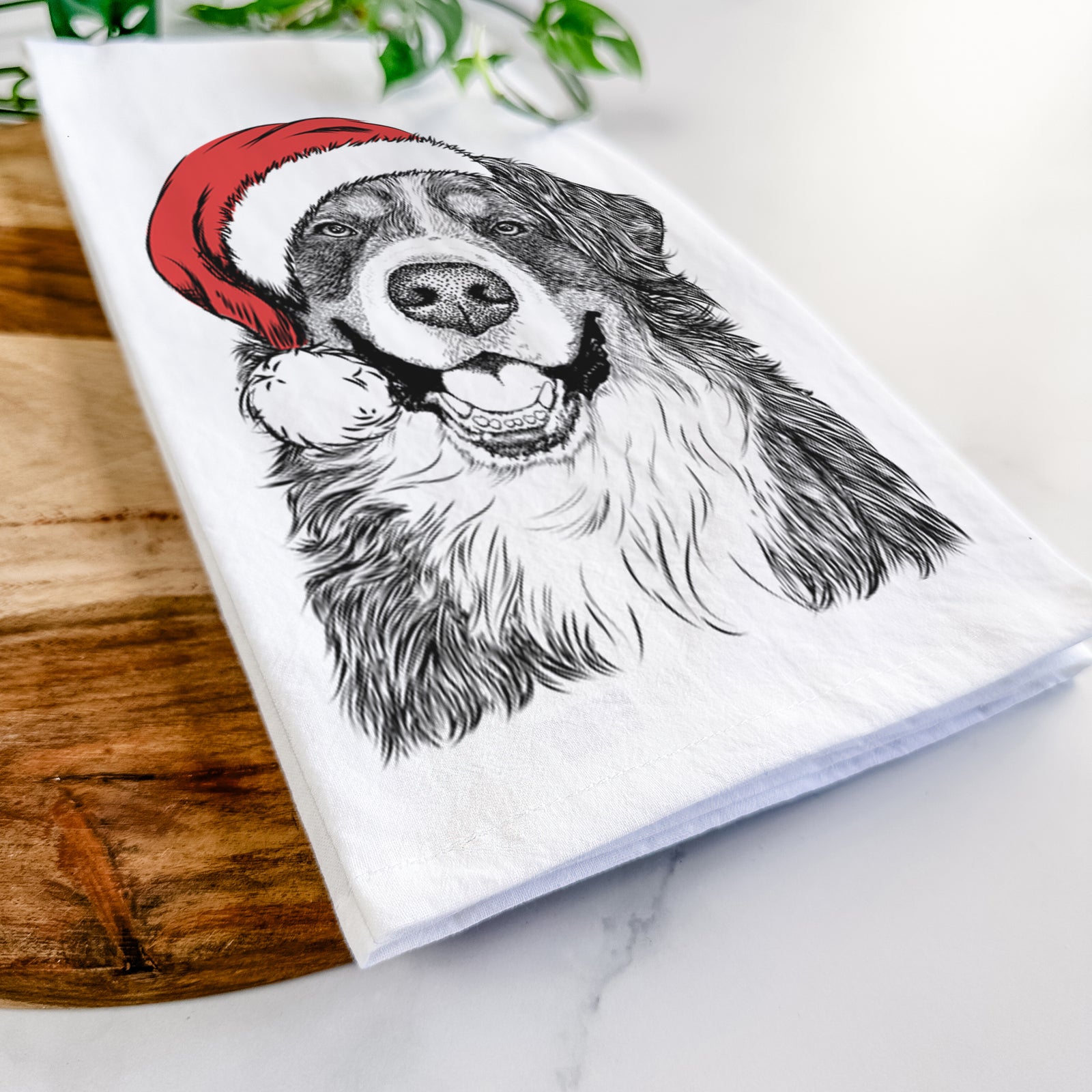 Hand-drawn sketch of Eiger the Bernese Mountain Dog wearing a Santa hat on a tea towel