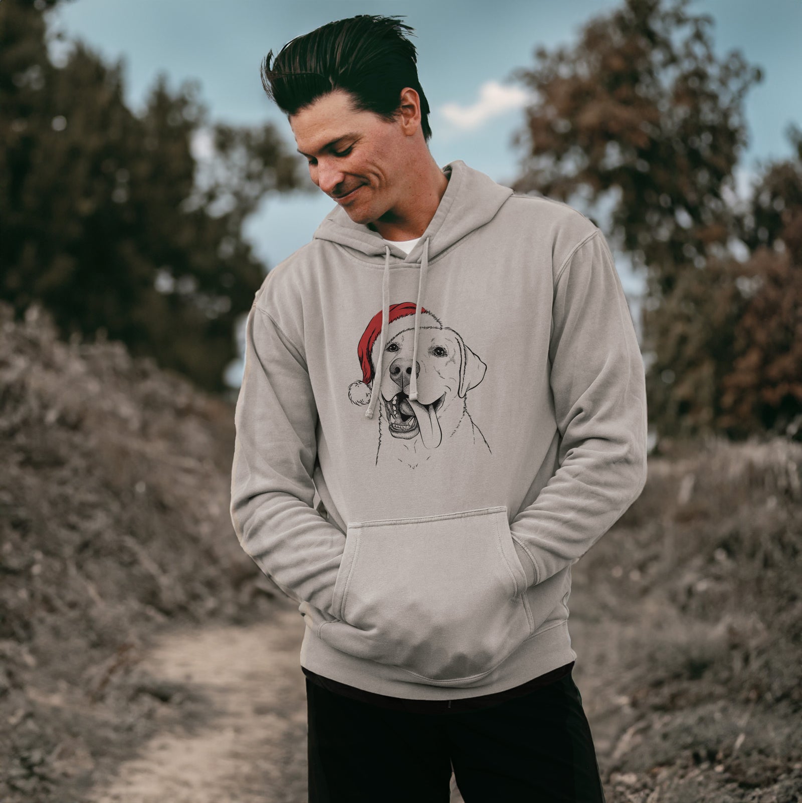Hand-drawn sketch of Finn the Labrador Retriever wearing a Santa hat on a Cement Unisex pigment dyed hoodie, worn by a man