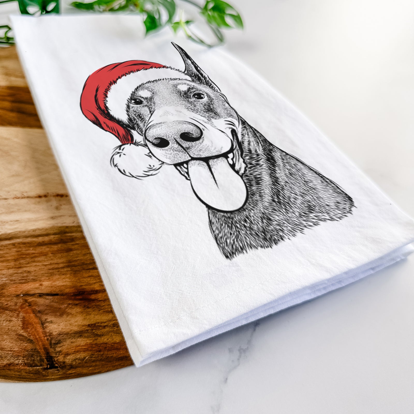 Hand-drawn sketch of Happy Sunny the Doberman Pinscher wearing a Santa hat on a tea towel