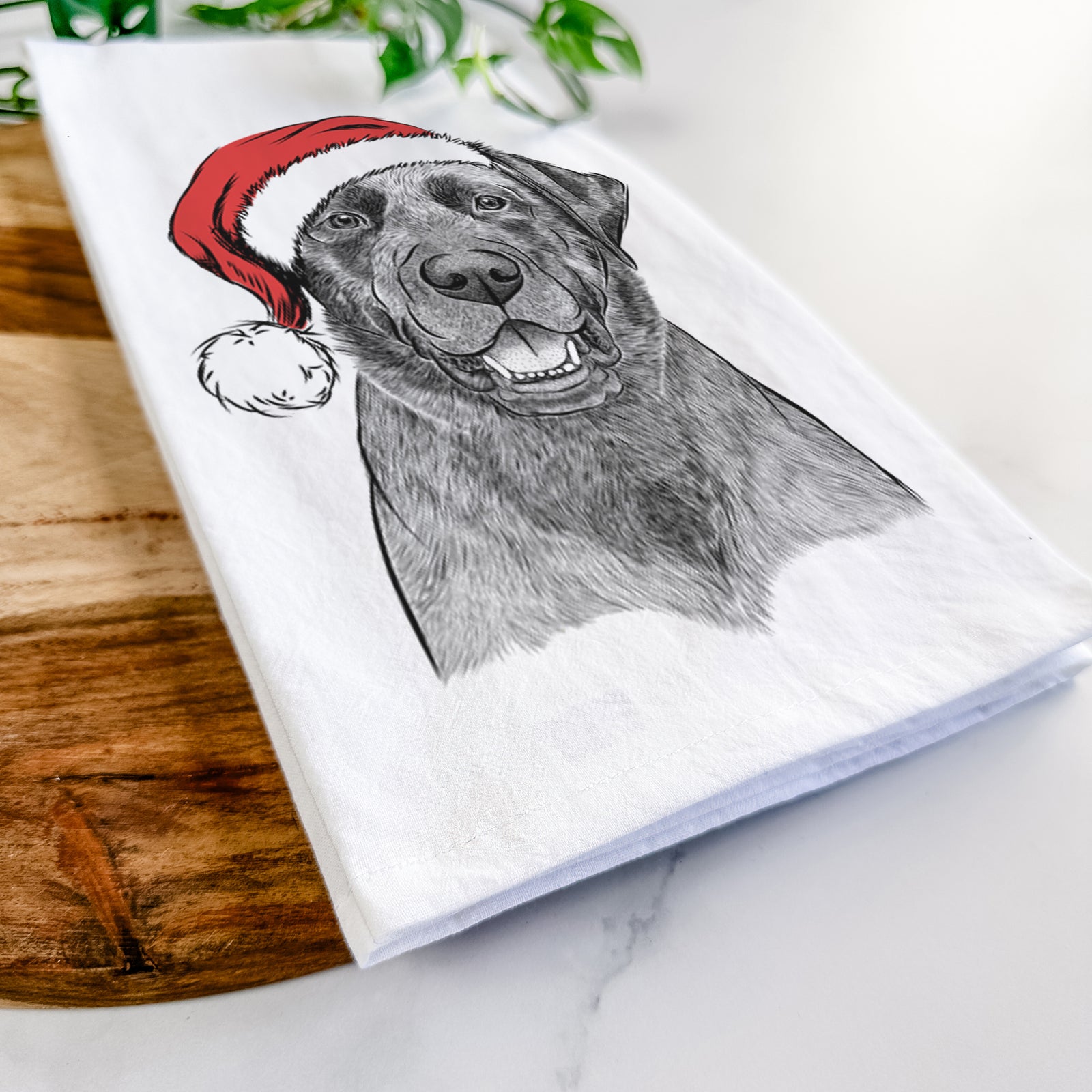 Hand-drawn sketch of Heath the Black Lab wearing a Santa hat on a tea towel