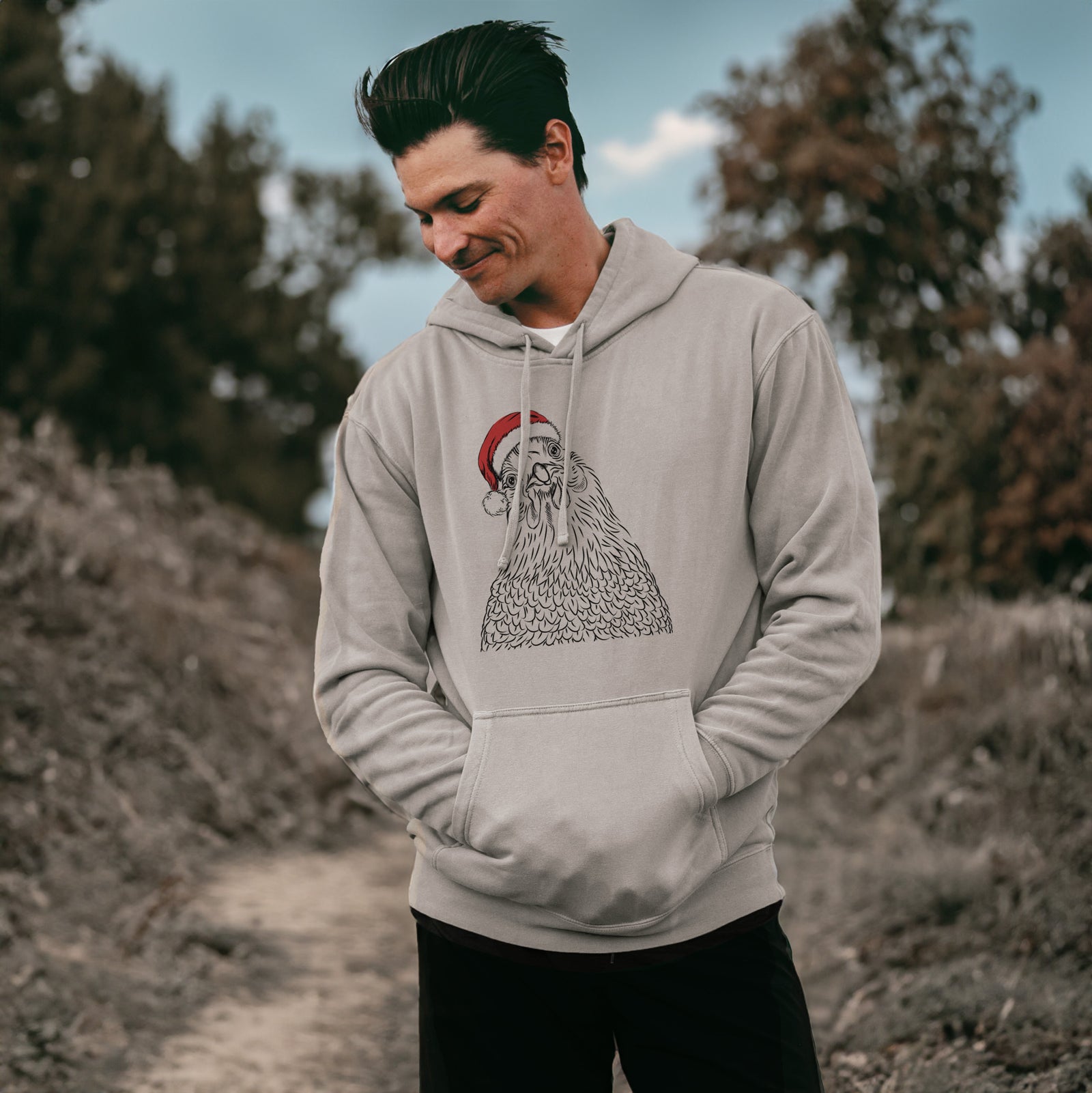 Hand-drawn sketch of Henrietta the Chicken wearing a Santa hat on a Cement Unisex pigment dyed hoodie, worn by a man