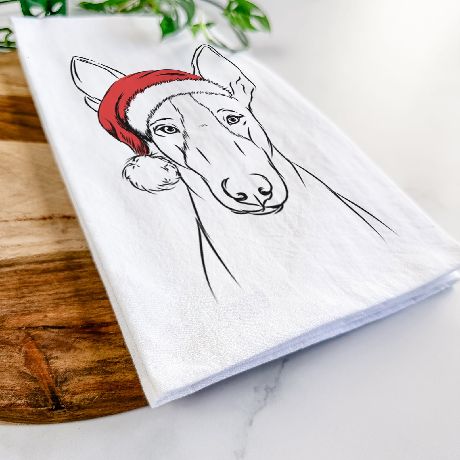 Hand-drawn sketch of Indy the Ibizan Hound wearing a Santa hat on a tea towel