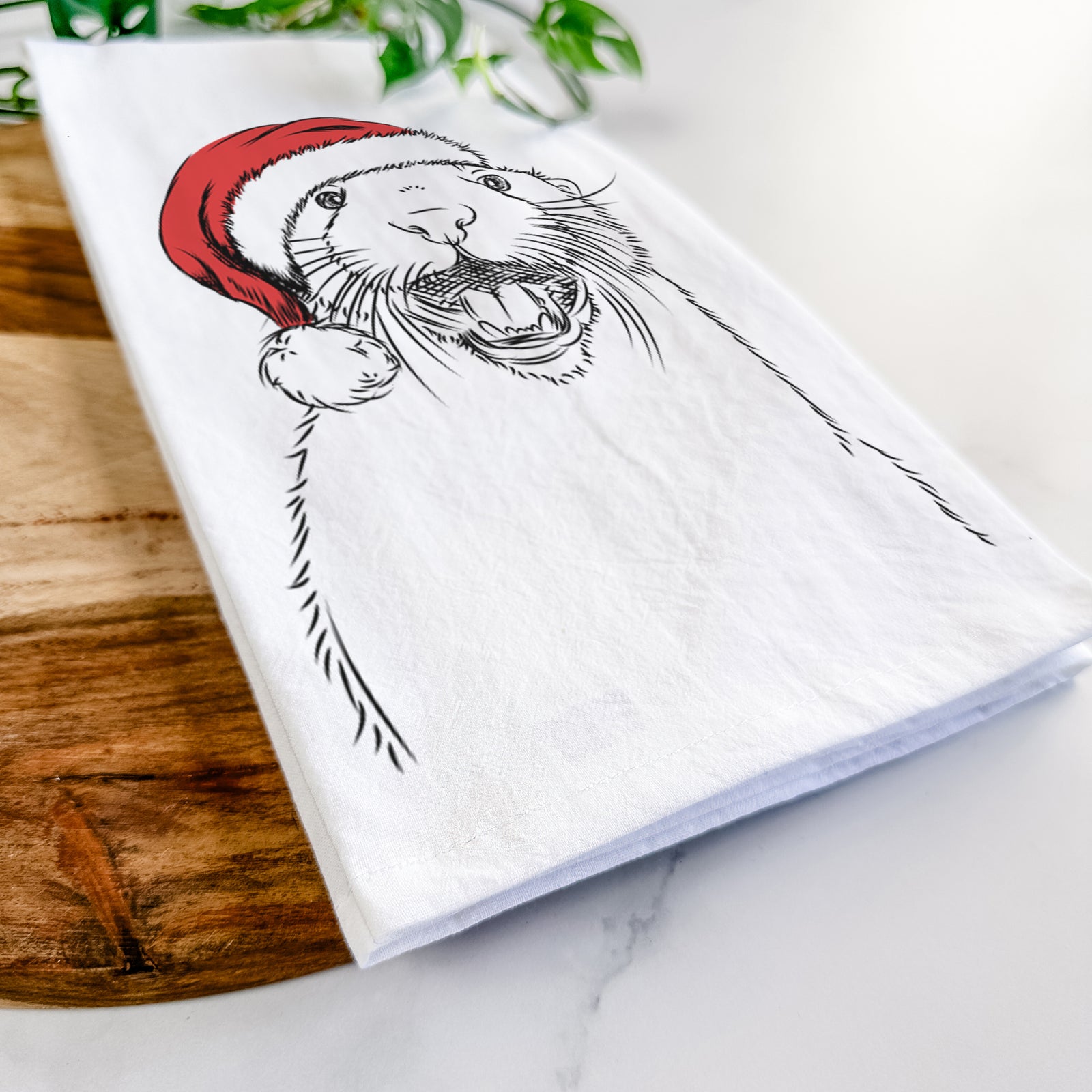 Hand-drawn sketch of Jasper the River Otter wearing a Santa hat on a tea towel
