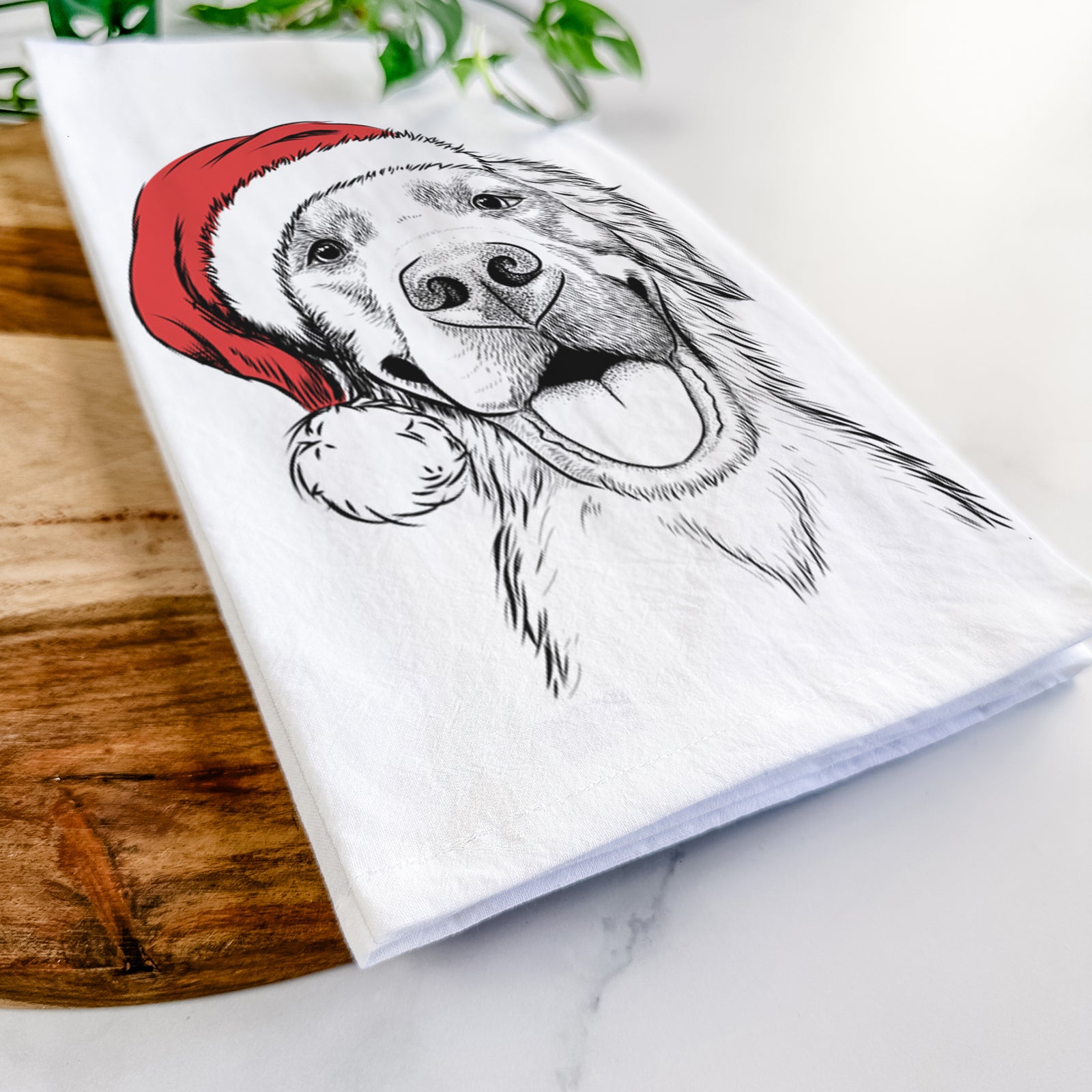 Hand-drawn sketch of Jordy the Golden Retriever wearing a Santa hat on a tea towel