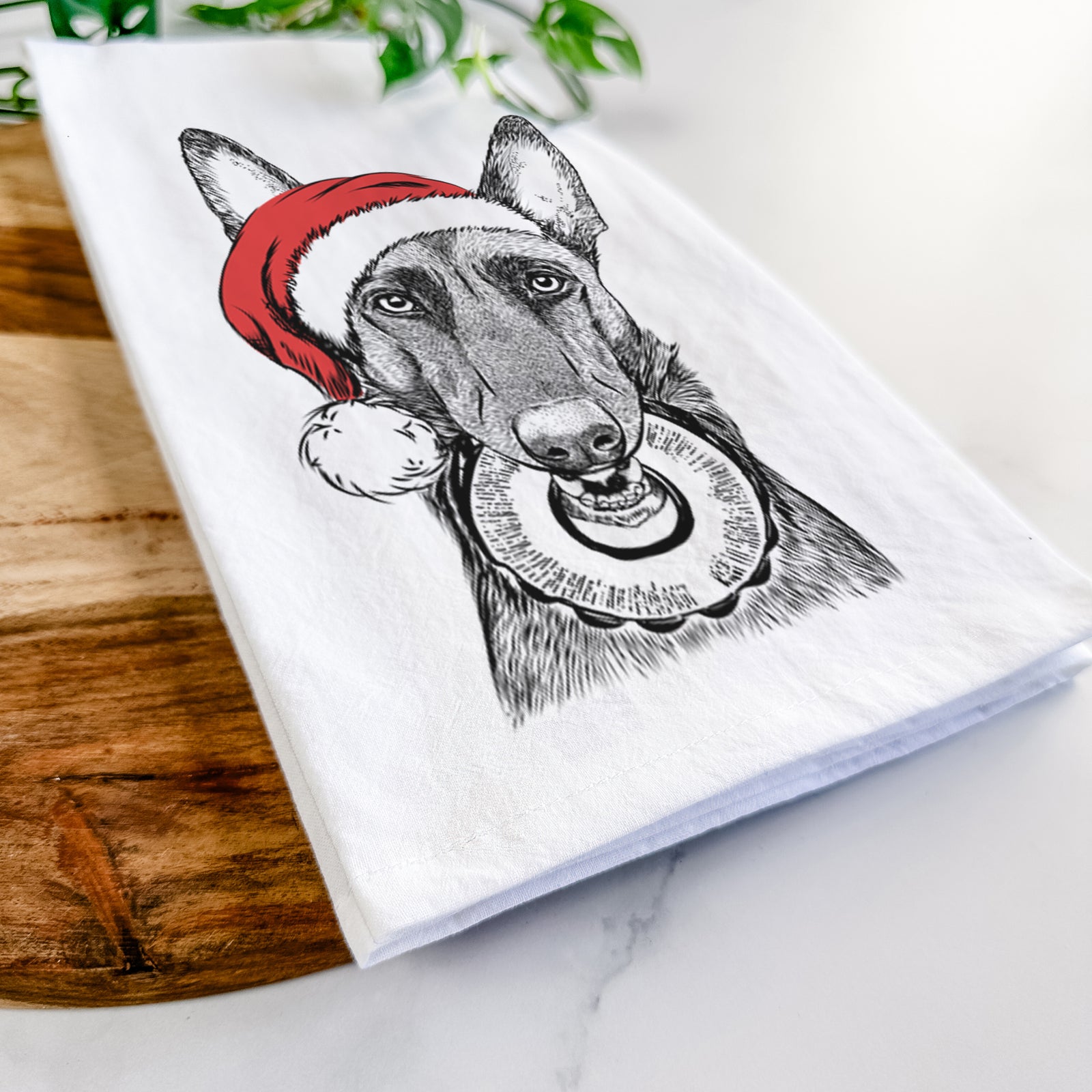 Hand-drawn sketch of Juno the Belgian Malinois wearing a Santa hat on a tea towel