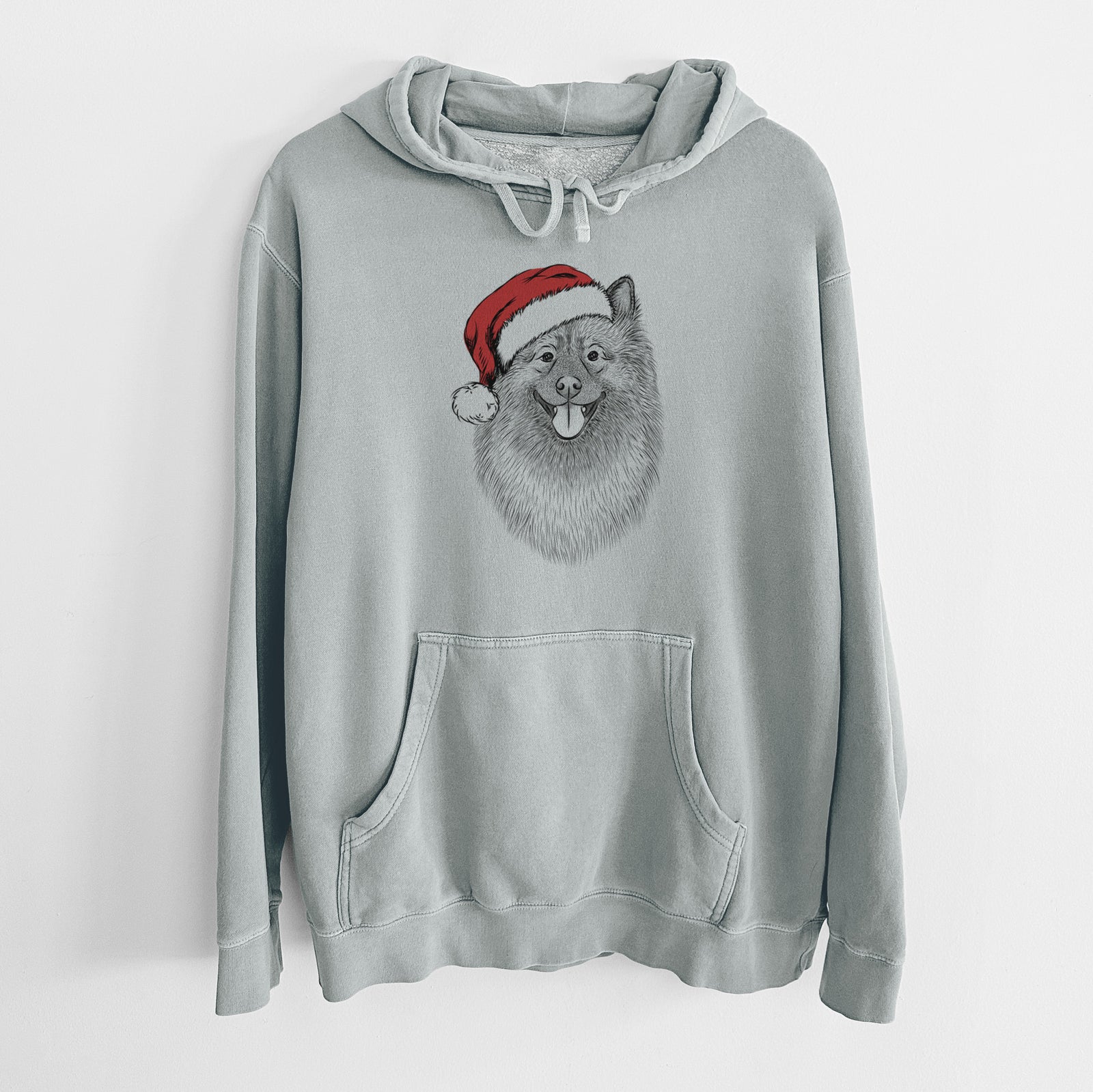 Hand-drawn sketch of Kai the Keeshond wearing a Santa hat on a Sage Unisex pigment dyed hoodie