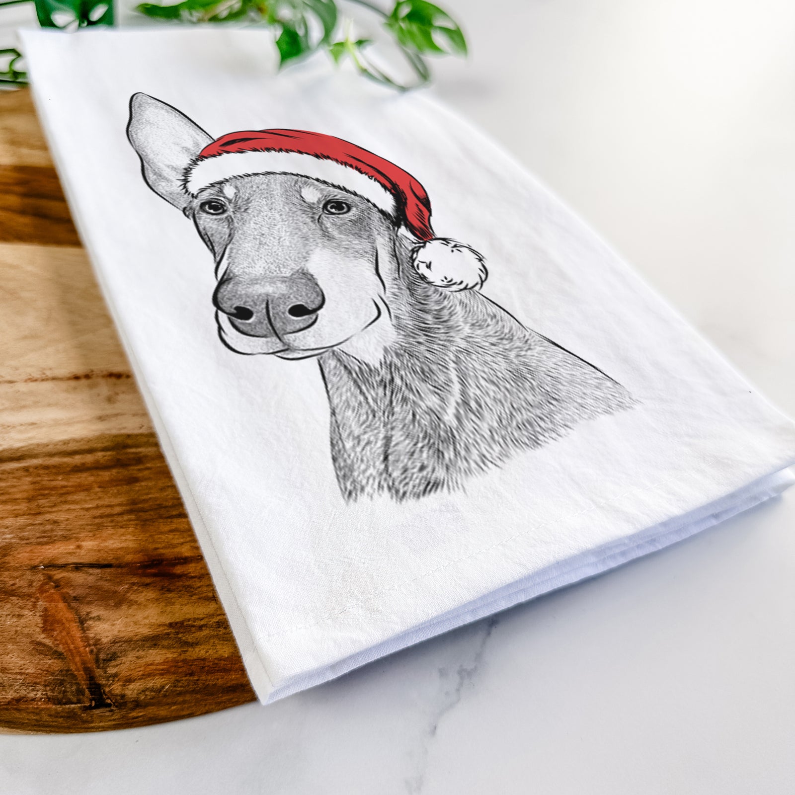 Hand-drawn sketch of Kain the Doberman Pinscher wearing a Santa hat on a tea towel