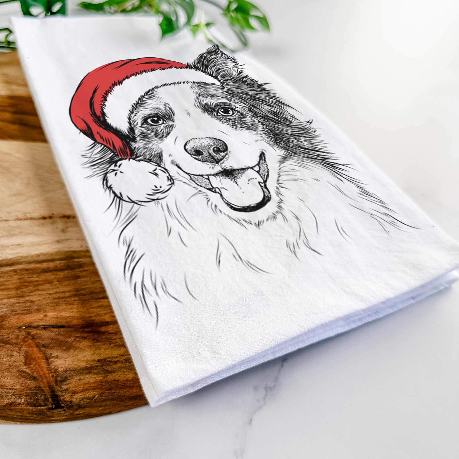 Hand-drawn sketch of Kylee the Border Collie wearing a Santa hat on a tea towel