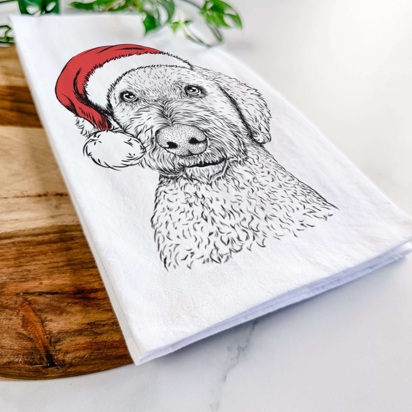 Hand-drawn sketch of Lucy Boo the Goldendoodle wearing a Santa hat on a tea towel