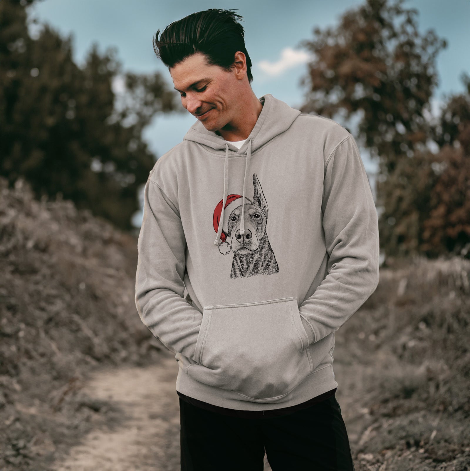Hand-drawn sketch of Luna the Doberman Pinscher wearing a Santa hat on a Cement Unisex pigment dyed hoodie, worn by a man