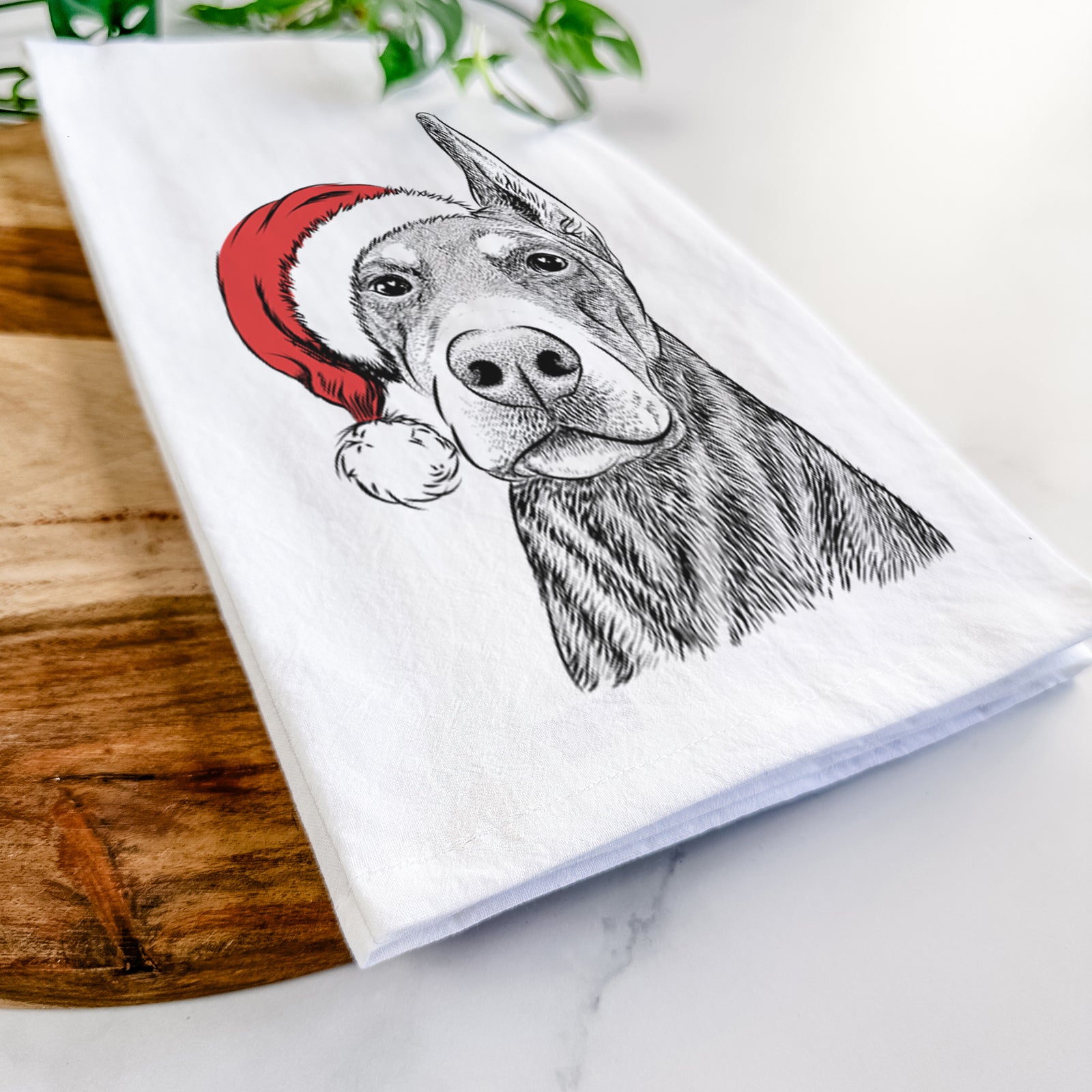Hand-drawn sketch of Luna the Doberman Pinscher wearing a Santa hat on a tea towel