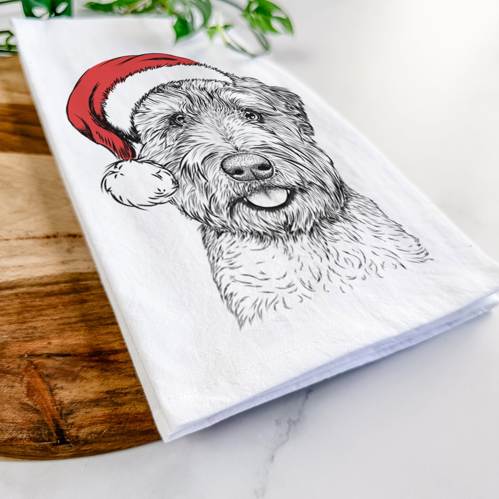 Hand-drawn sketch of Milton the Soft Coated Wheaten Terrier wearing a Santa hat on a tea towel