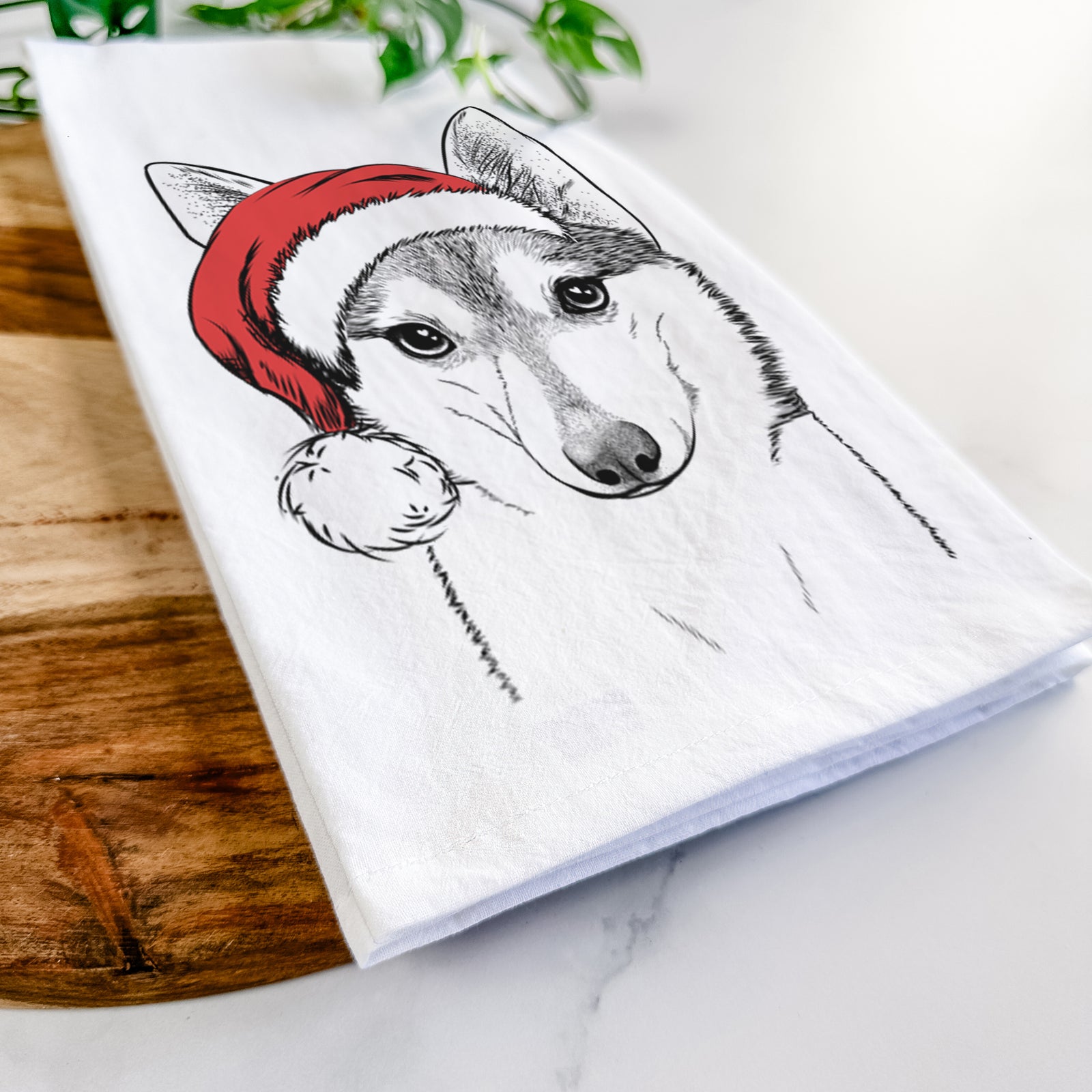 Hand-drawn sketch of Nami the Alaskan Klee Kai wearing a Santa hat on a tea towel
