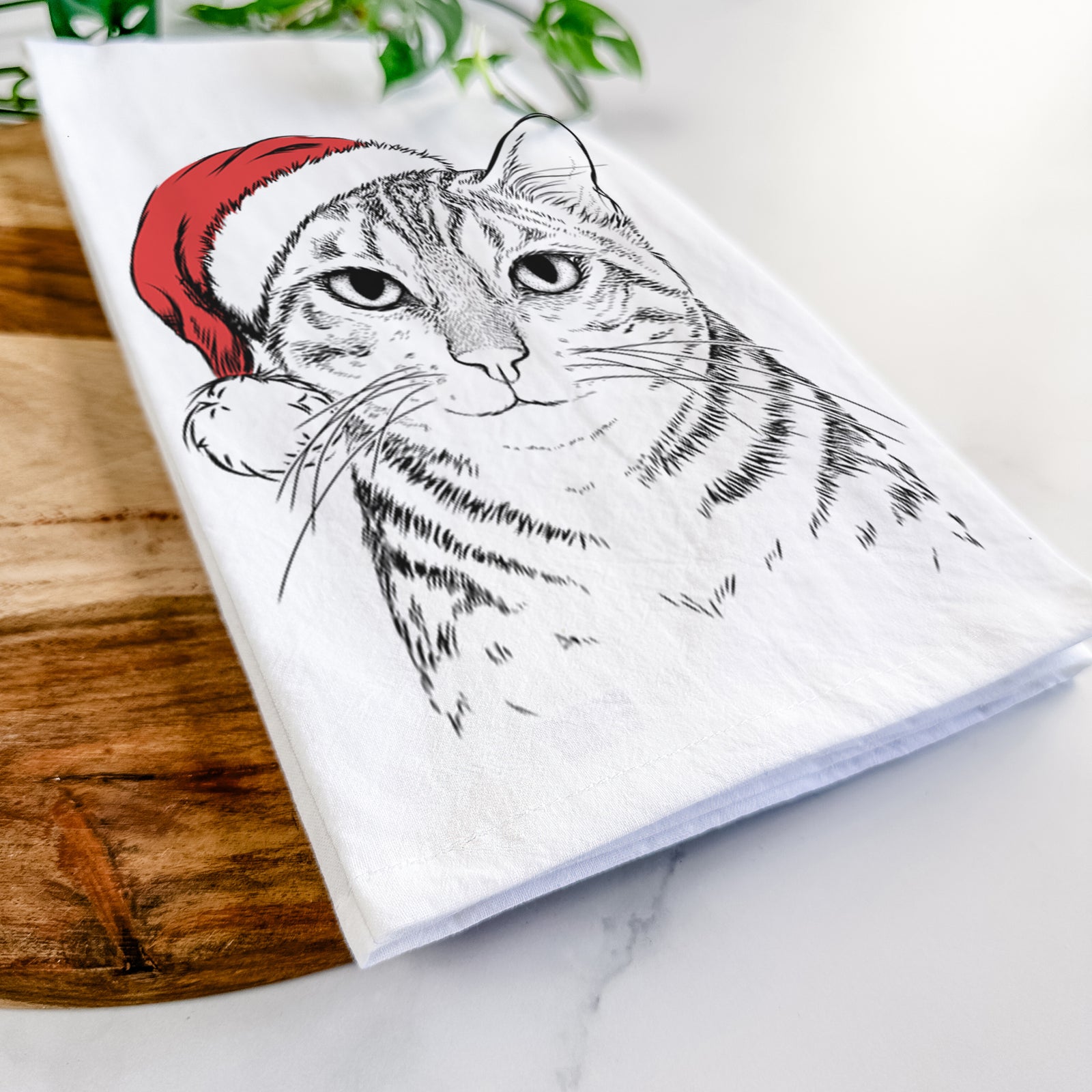 Hand-drawn sketch of Nell the Tabby Cat wearing a Santa hat on a tea towel