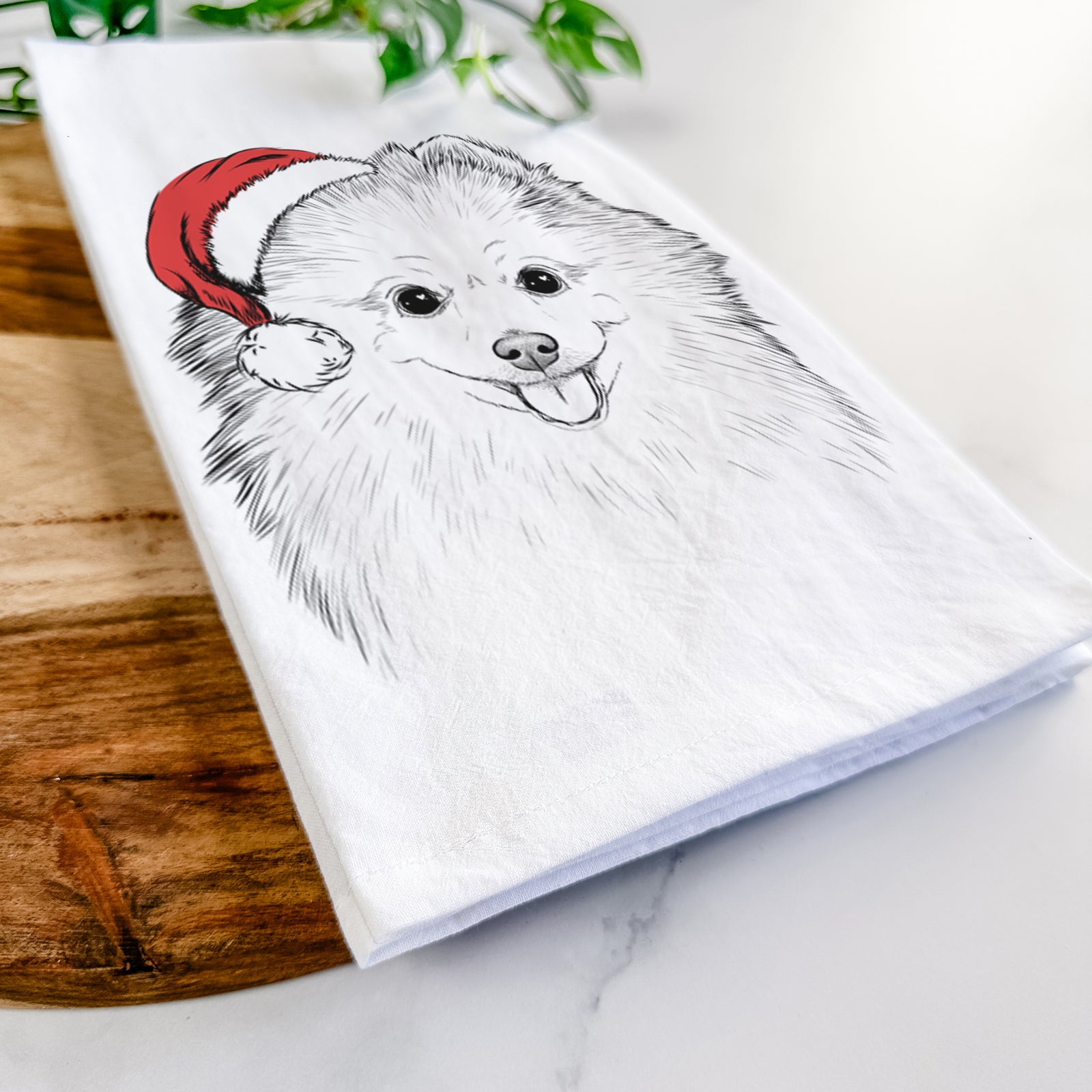 Hand-drawn sketch of Piper Jo the Pomeranian wearing a Santa hat on a tea towel
