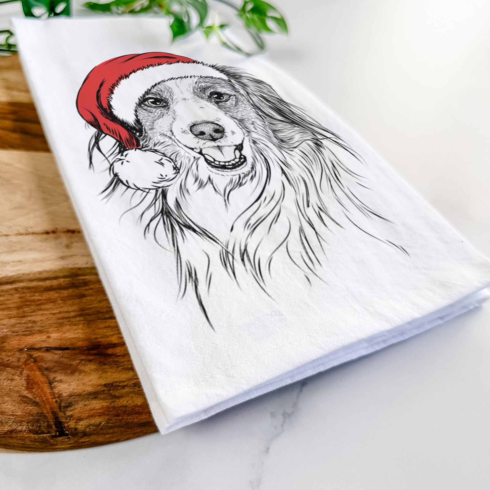 Hand-drawn sketch of Rutger the Nederlandse Kooikerhondje wearing a Santa hat on a tea towel