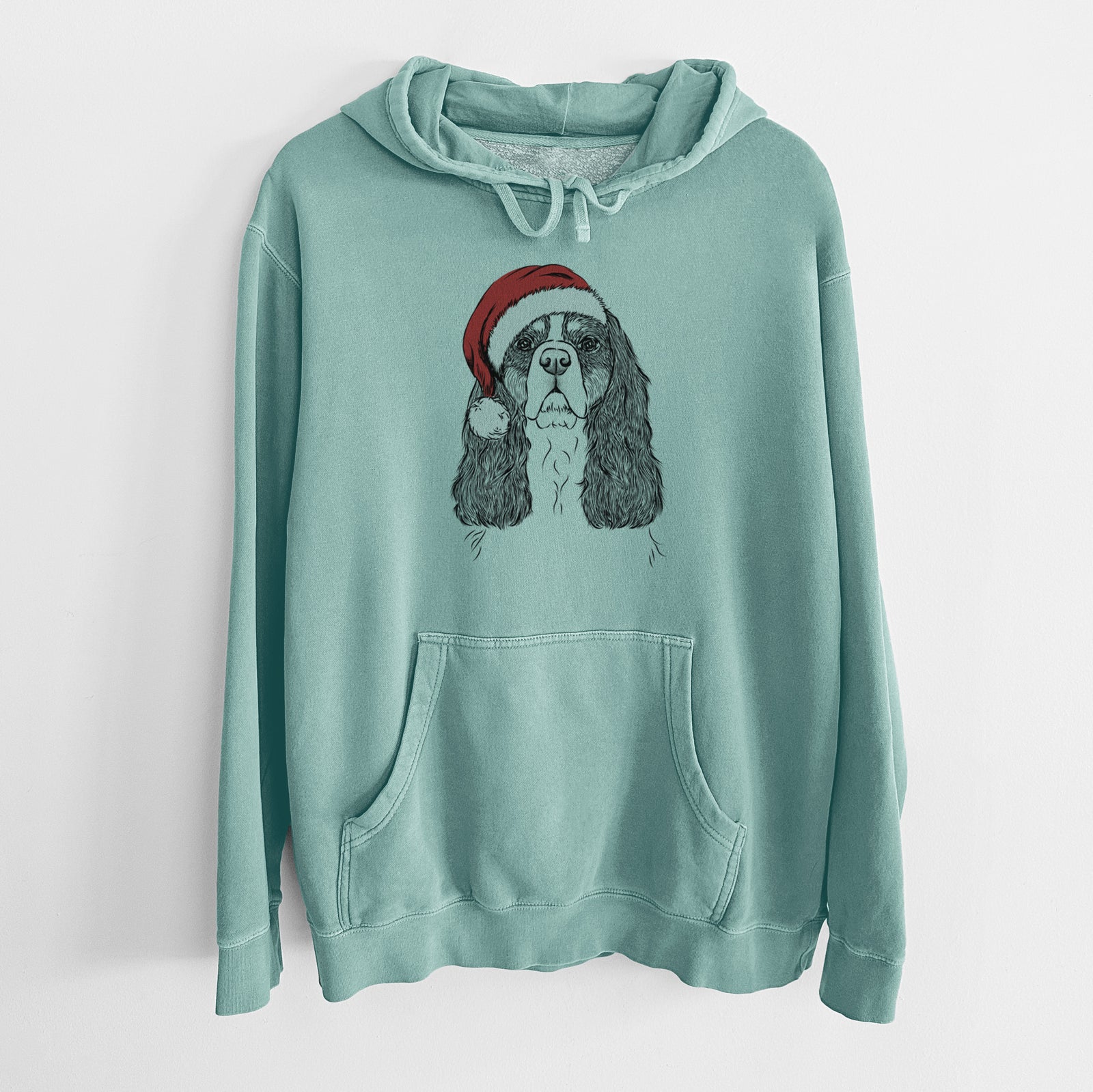Hand-drawn sketch of Sebastian the Cavalier King Charles Spaniel wearing a Santa hat on a Mint Unisex pigment dyed hoodie