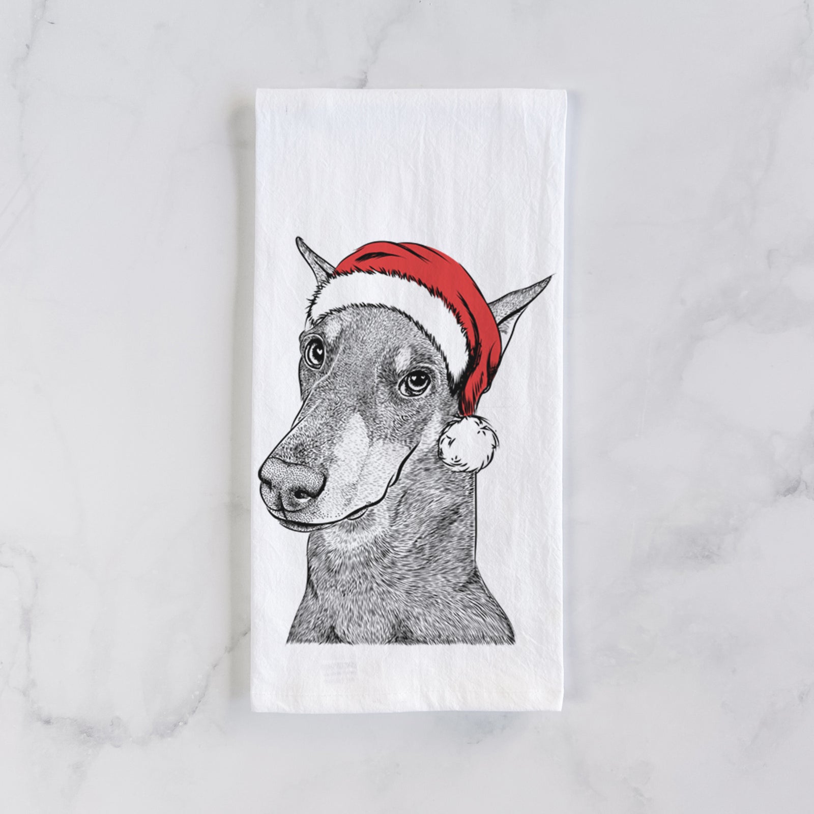 Hand-drawn sketch of Shelby the Doberman Pinscher wearing a Santa hat on a tea towel