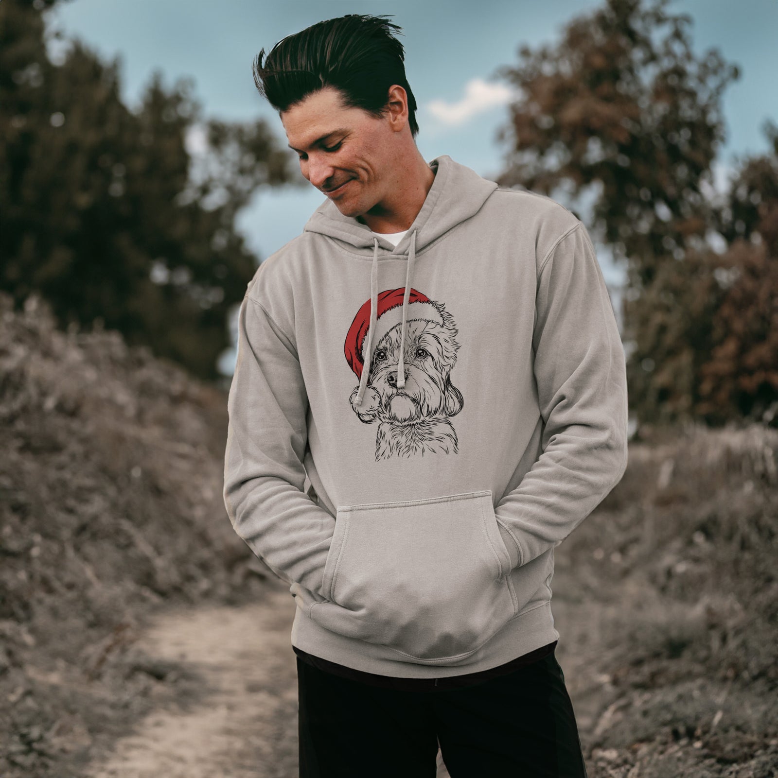 Hand-drawn sketch of Sir Walter the Dandie Dinmont Terrier wearing a Santa hat on a Cement Unisex pigment dyed hoodie, worn by a man