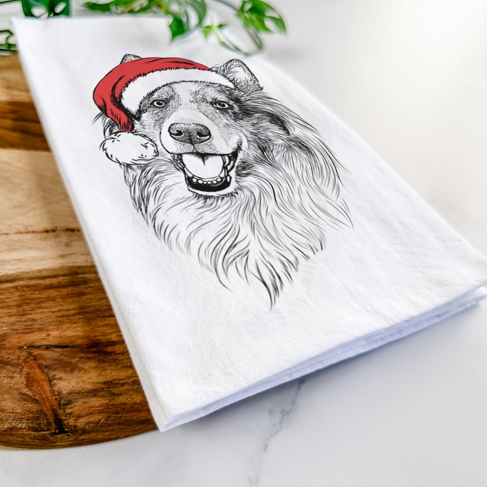 Hand-drawn sketch of Skylar the Shetland Sheepdog wearing a Santa hat on a tea towel