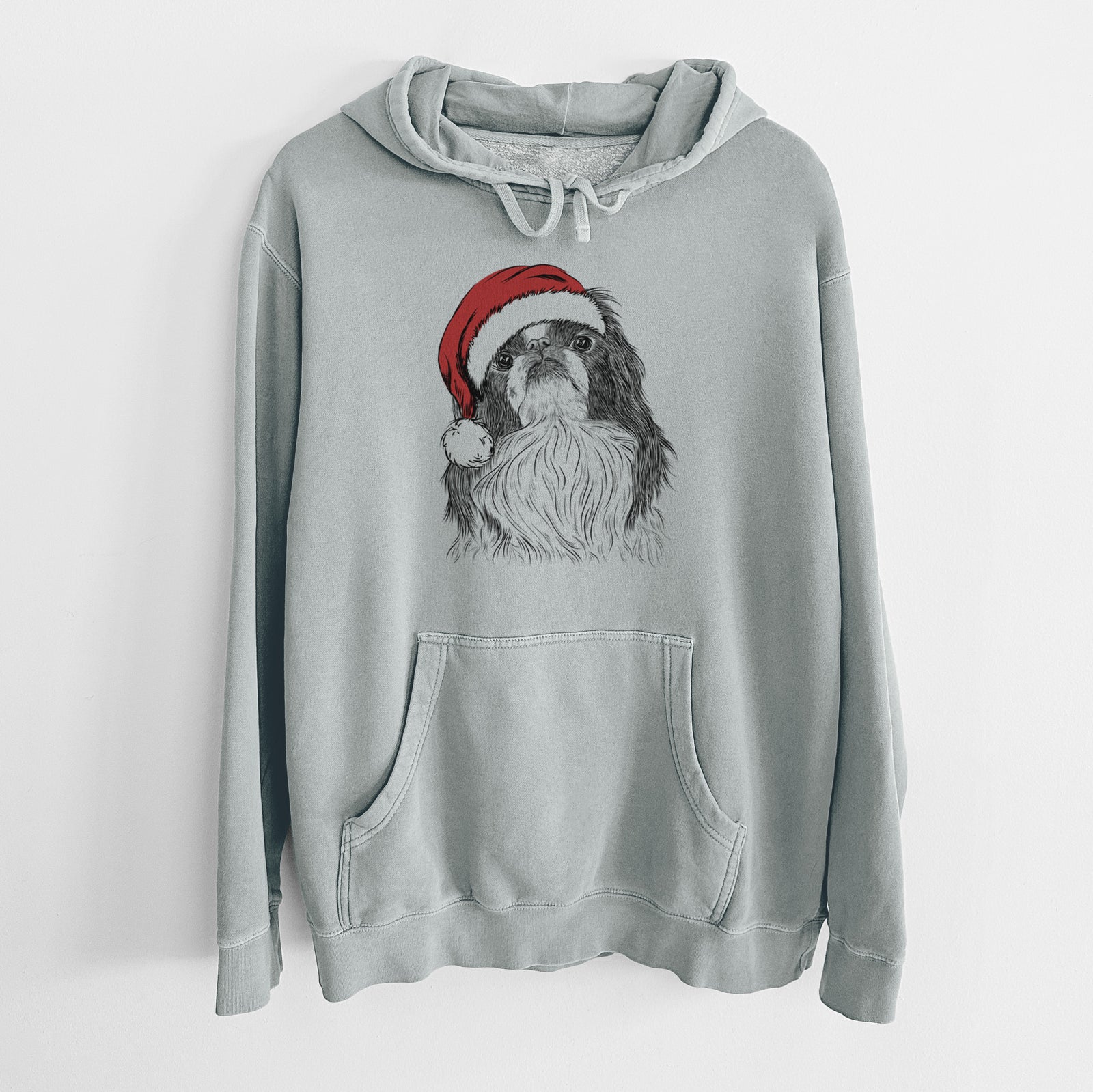 Hand-drawn sketch of Suki the Japanese Chin wearing a Santa hat on a Sage Unisex pigment dyed hoodie